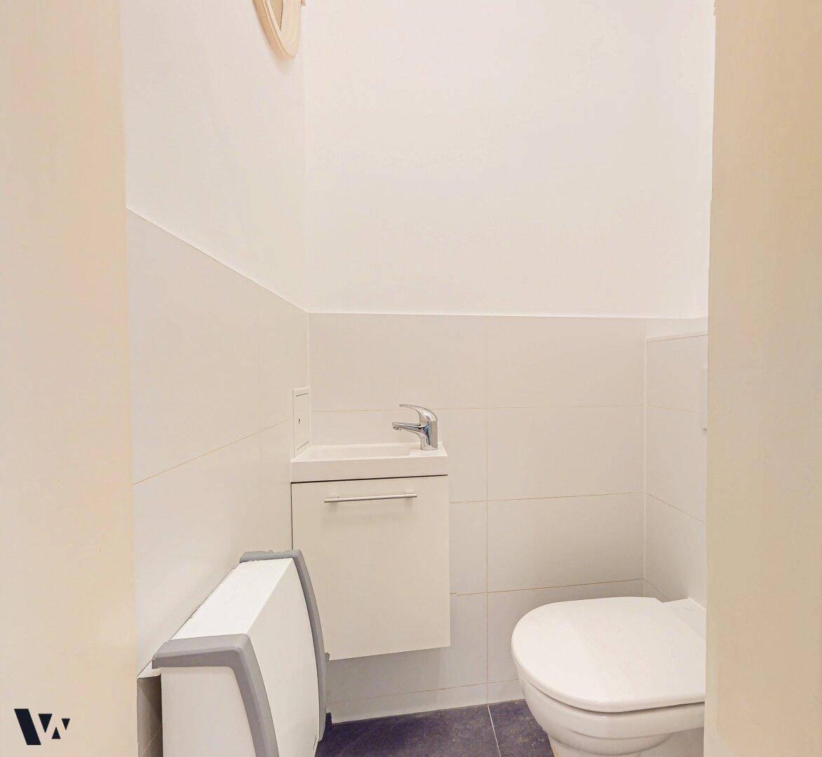 Separates Gäste-WC mit wandhängender Toilette und kleinem Handwaschbecken.