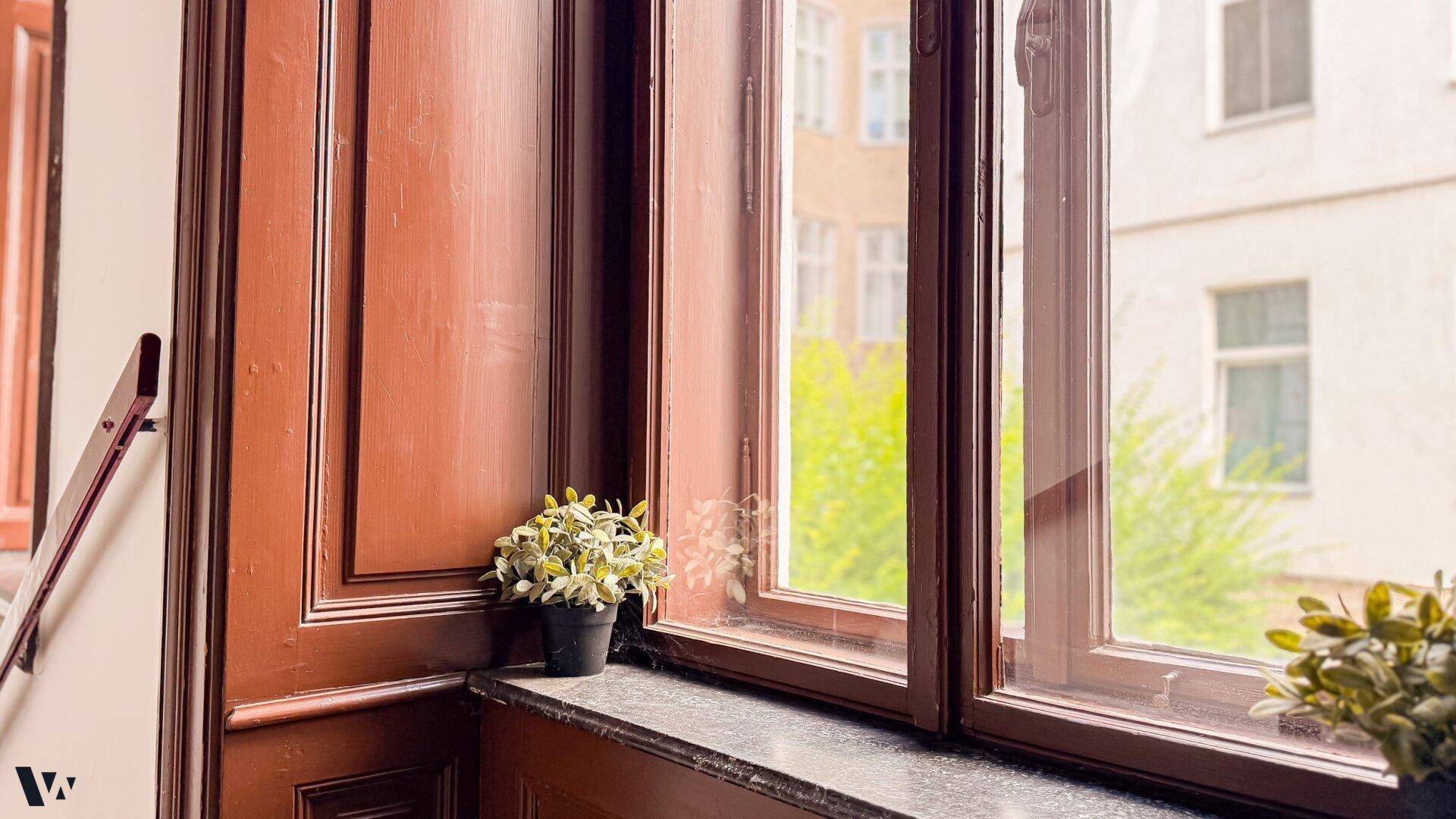 Detailansicht eines Fensters im Treppenhaus mit Blick ins Grüne und Holzelementen.