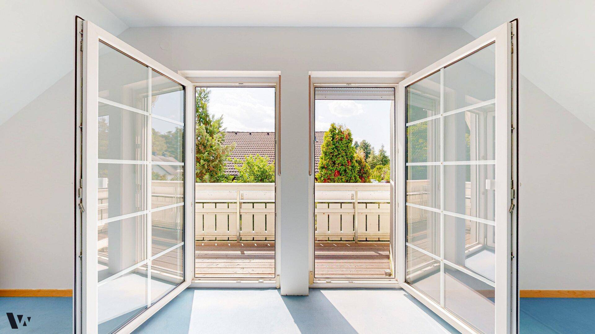 Große Fenstertüren im Dachgeschoss öffnen sich zu einem französischen Balkon mit Ausblick.