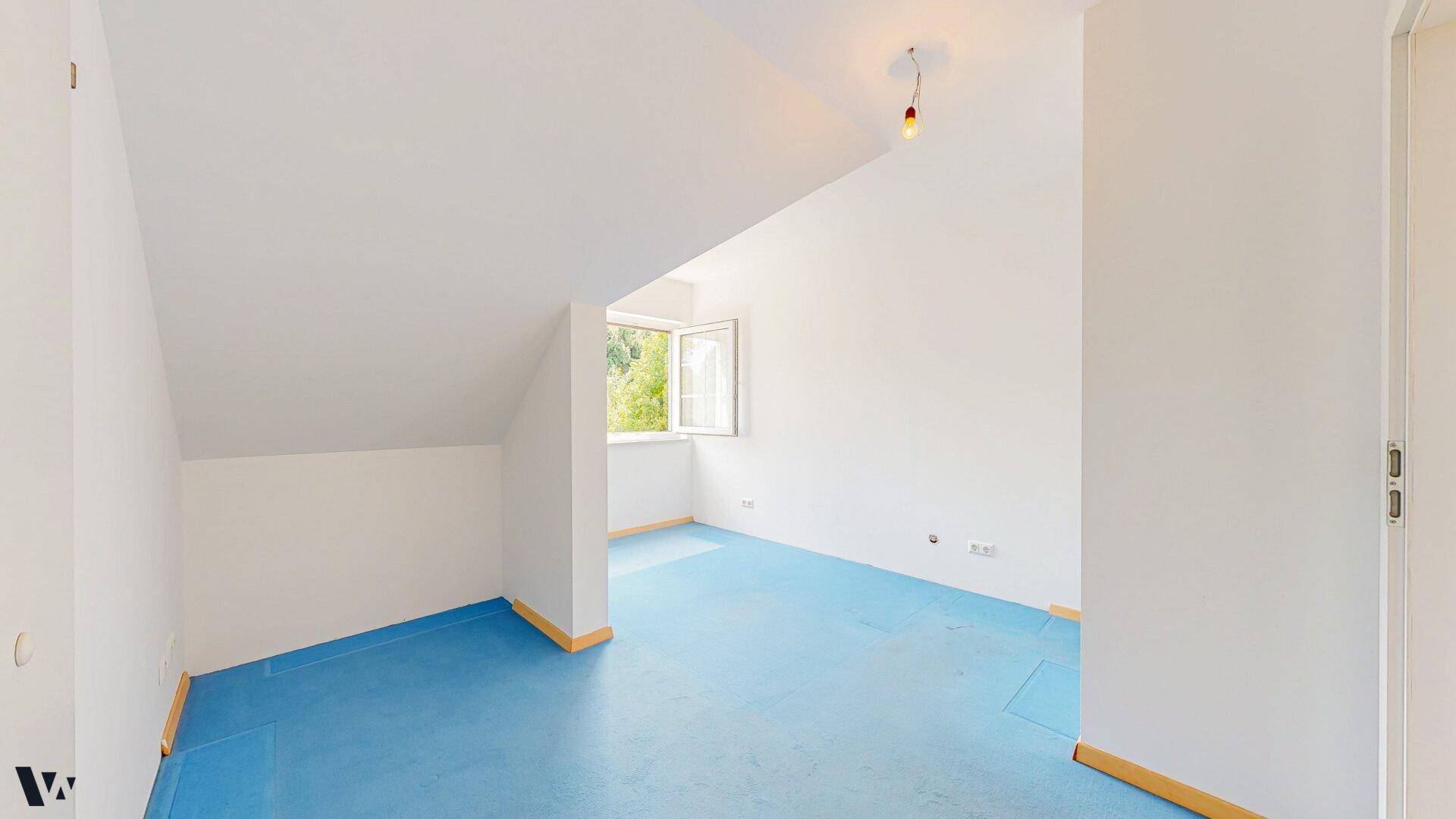 Leeres Dachgeschosszimmer mit schrägen Wänden und blauem Teppichboden, bereit zur individuellen Gestaltung.