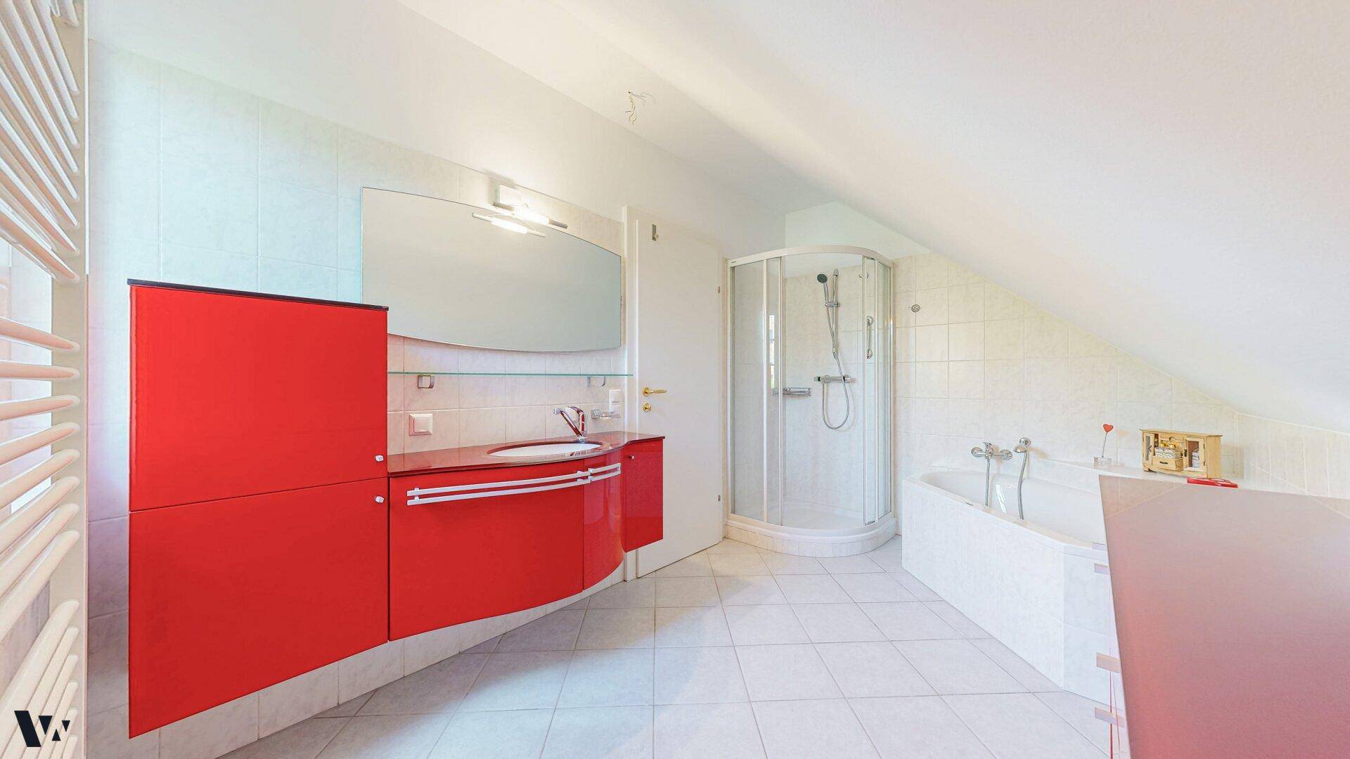 Geräumiges Badezimmer mit rotem Waschtisch, Dusche, Badewanne und beheiztem Handtuchhalter.