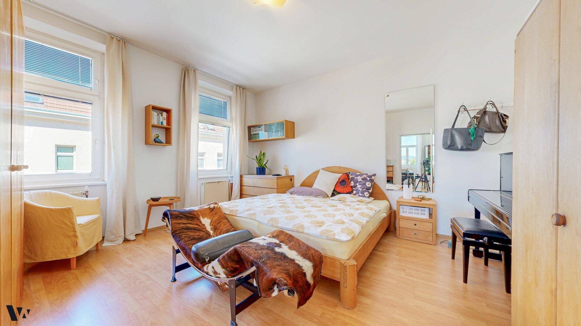 Schlafzimmer mit Holzboden, Doppelbett und einem Klavier, das eine ruhige Atmosphäre schafft.