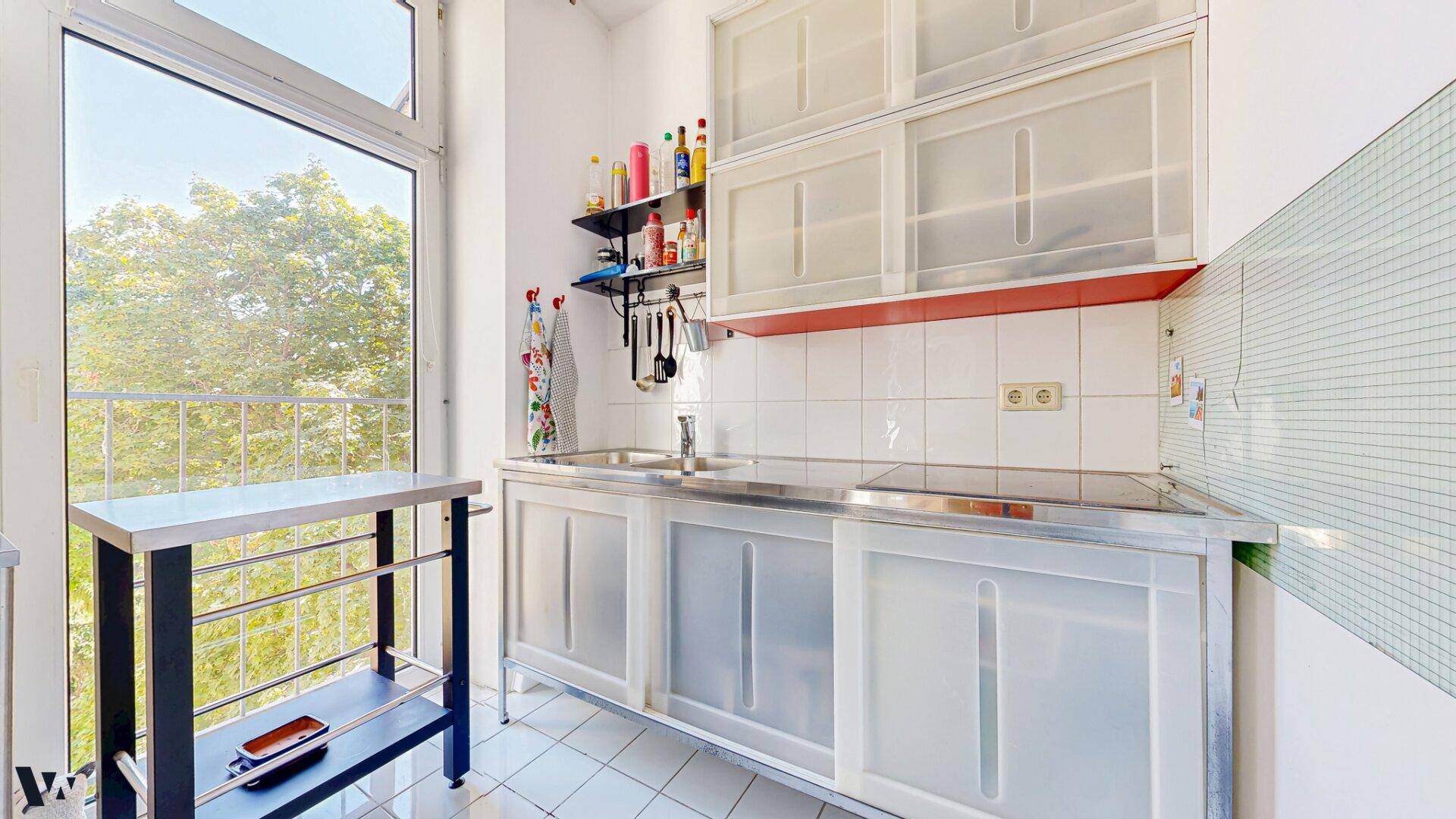 Kleine Küche mit Edelstahlmöbeln und Zugang zu einem Balkon, ideal für Singles oder als Zweitküche.