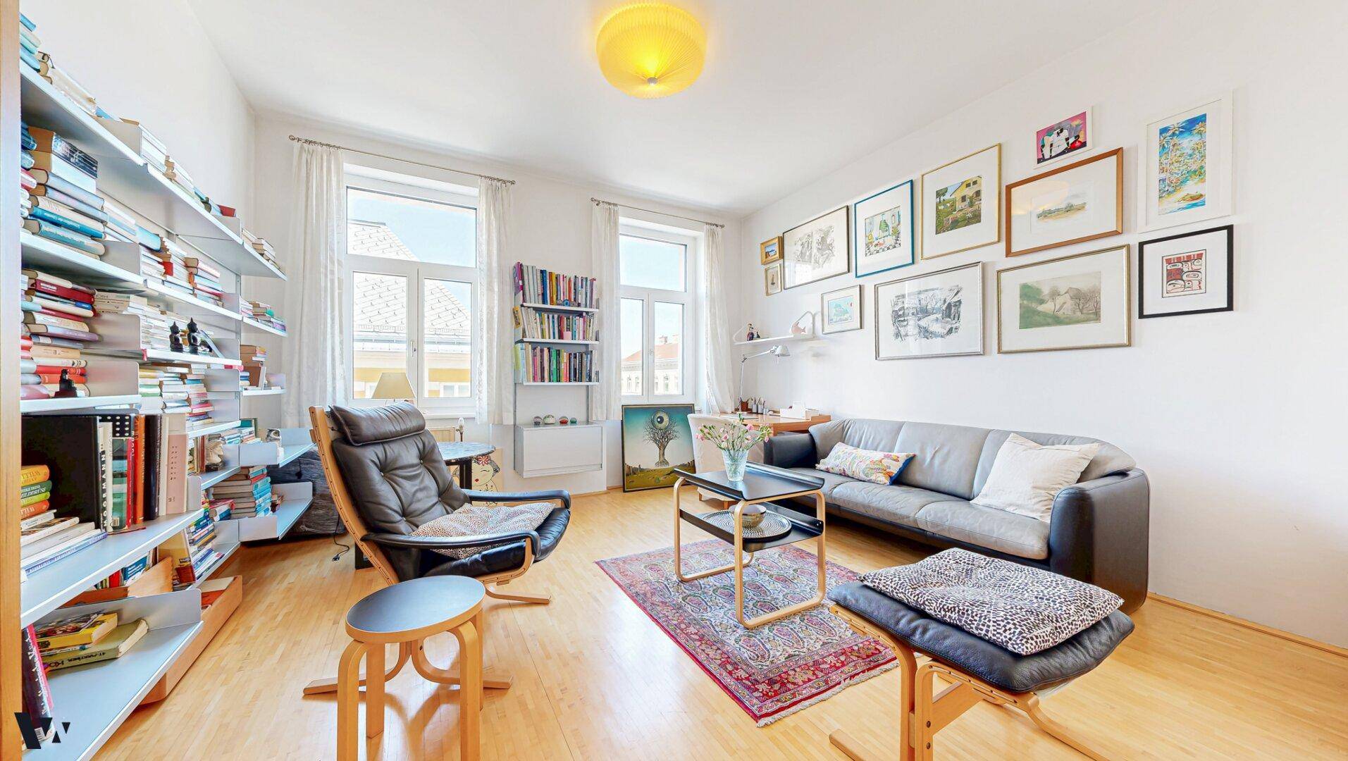 Gemütliches Wohnzimmer mit vielen Büchern, Holzboden und einem bequemen Sessel, ideal zum Entspannen.