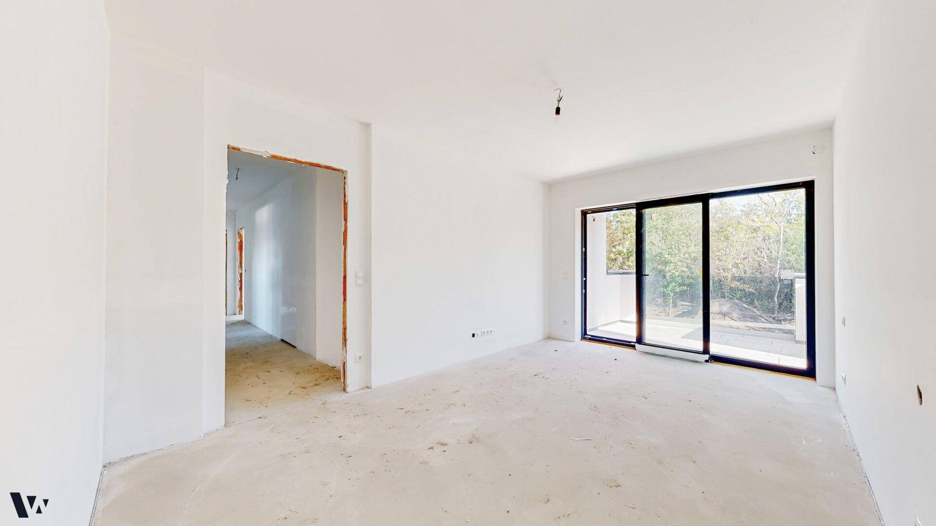 Helles Zimmer im Rohbau mit großen Schiebetüren, die auf einen Balkon führen.