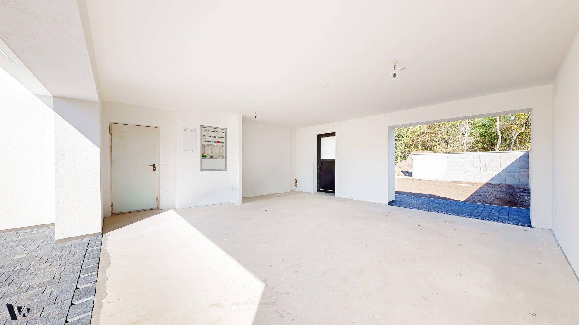 Geräumige Garage im Rohbau mit Zugang zum Außenbereich und viel Platz.