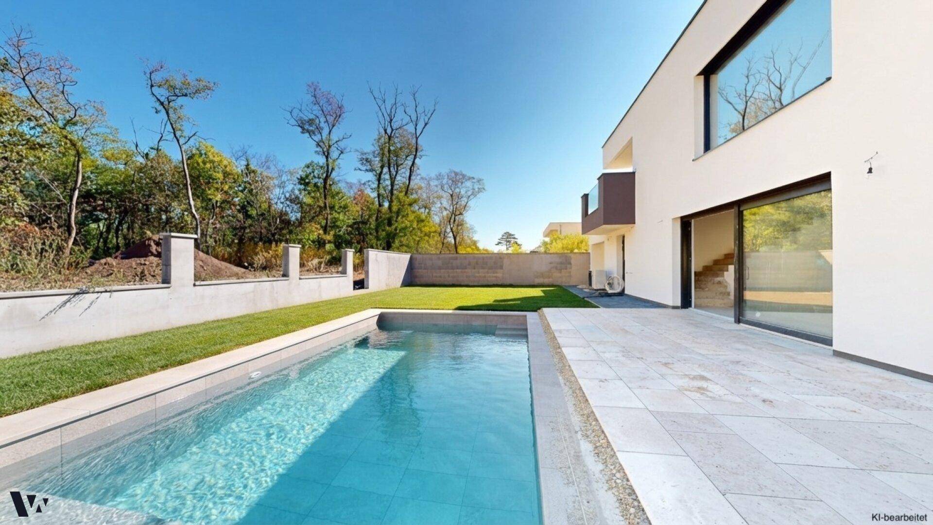 Seitlicher Blick auf den Swimmingpool und die Terrasse mit moderner Architektur im Hintergrund.