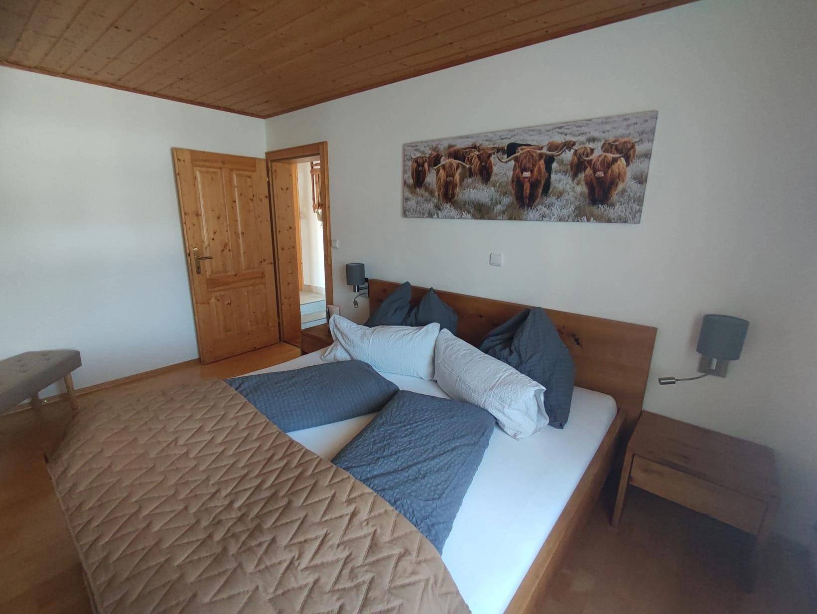 Gemütliches Schlafzimmer mit Doppelbett, Holzdecke und rustikaler Dekoration.