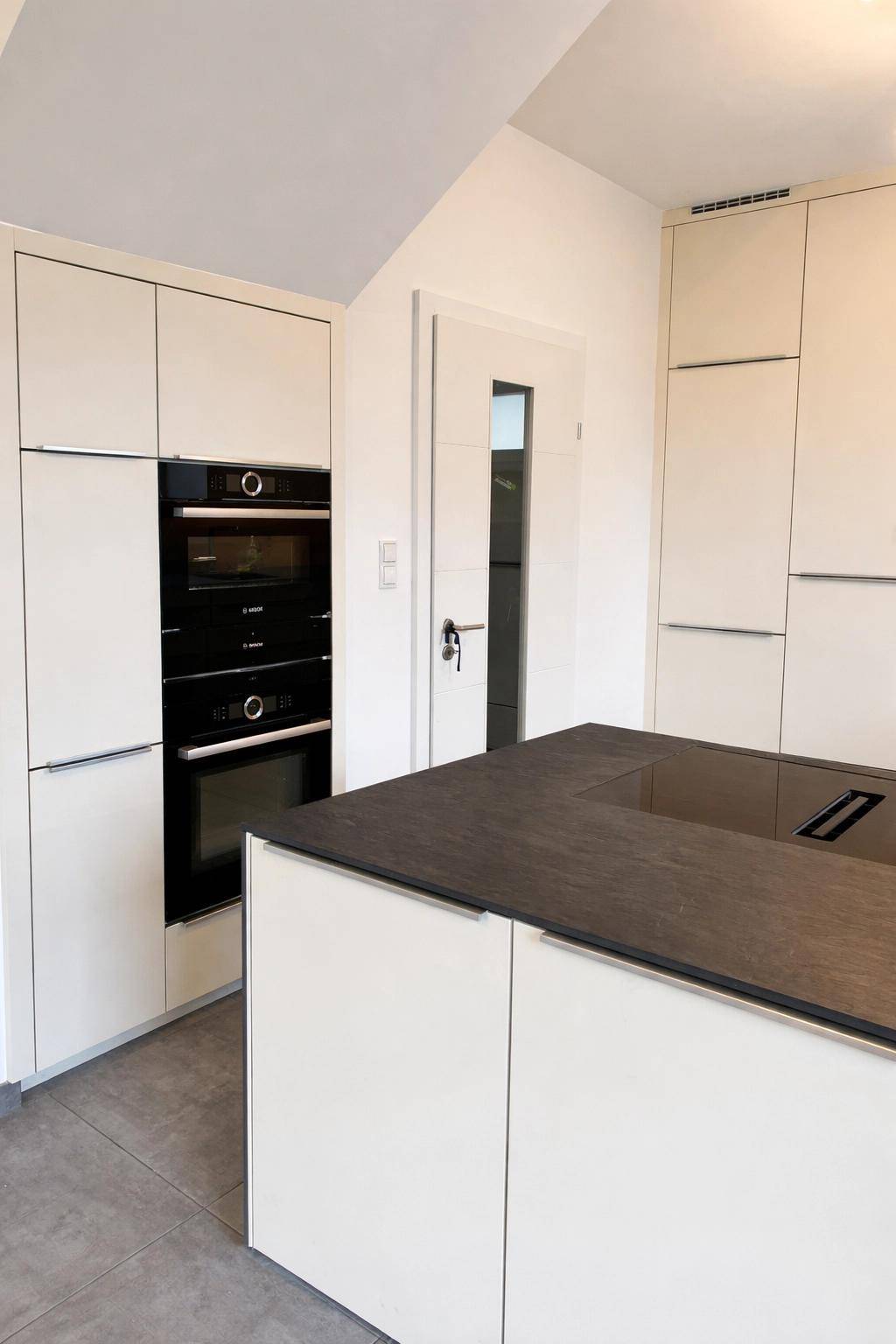Moderne Einbauküche mit integrierten Geräten und einer Kücheninsel in hellem Design.