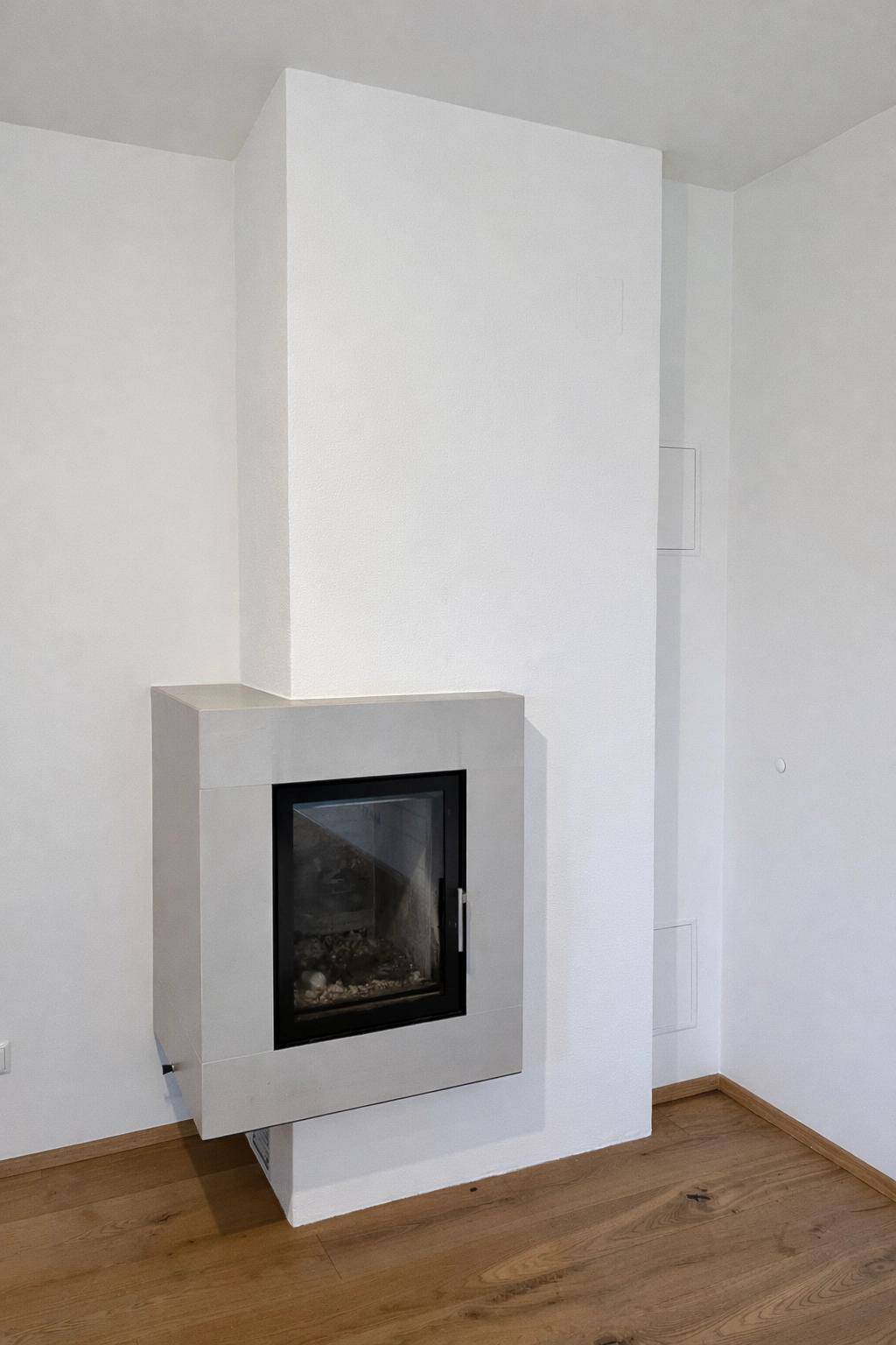 Moderner Kamin in einem hellen Raum mit Holzboden und minimalistischem Design.