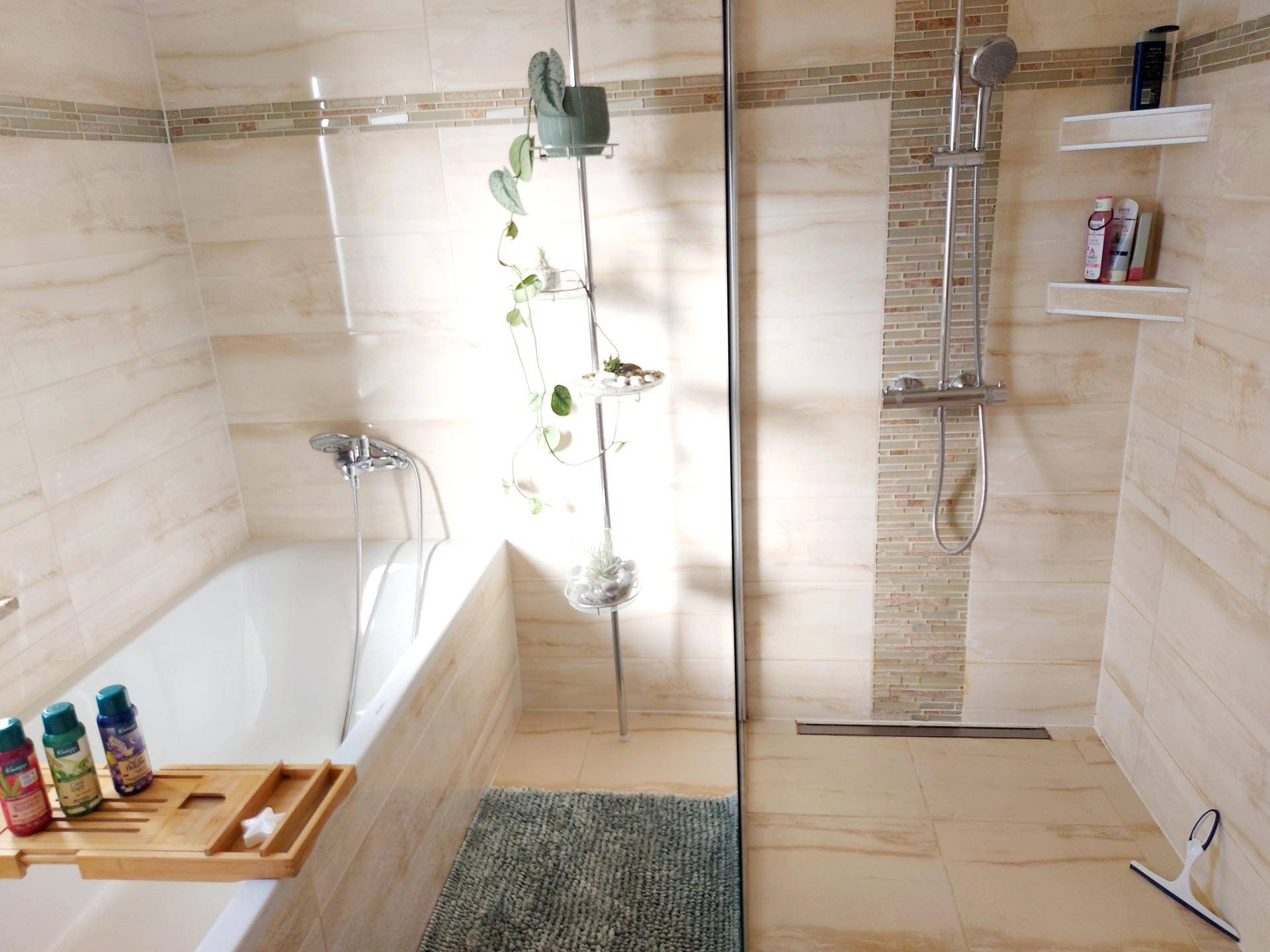 Modernes Badezimmer mit Badewanne, ebenerdiger Dusche und hellen Fliesen.
