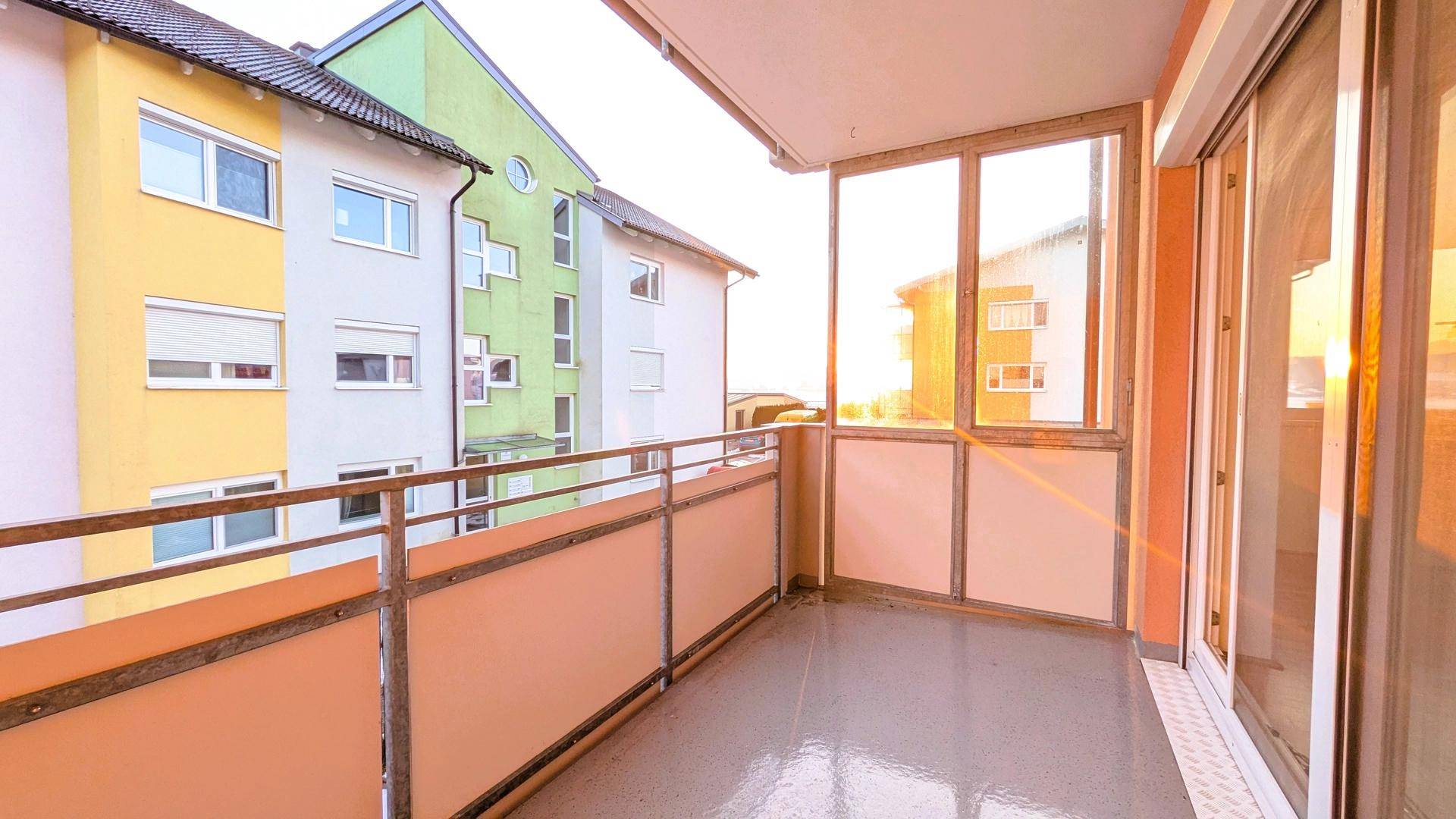 Heller Balkon mit Verglasung und Blick auf die umliegenden Gebäude, ideal zum Entspannen.