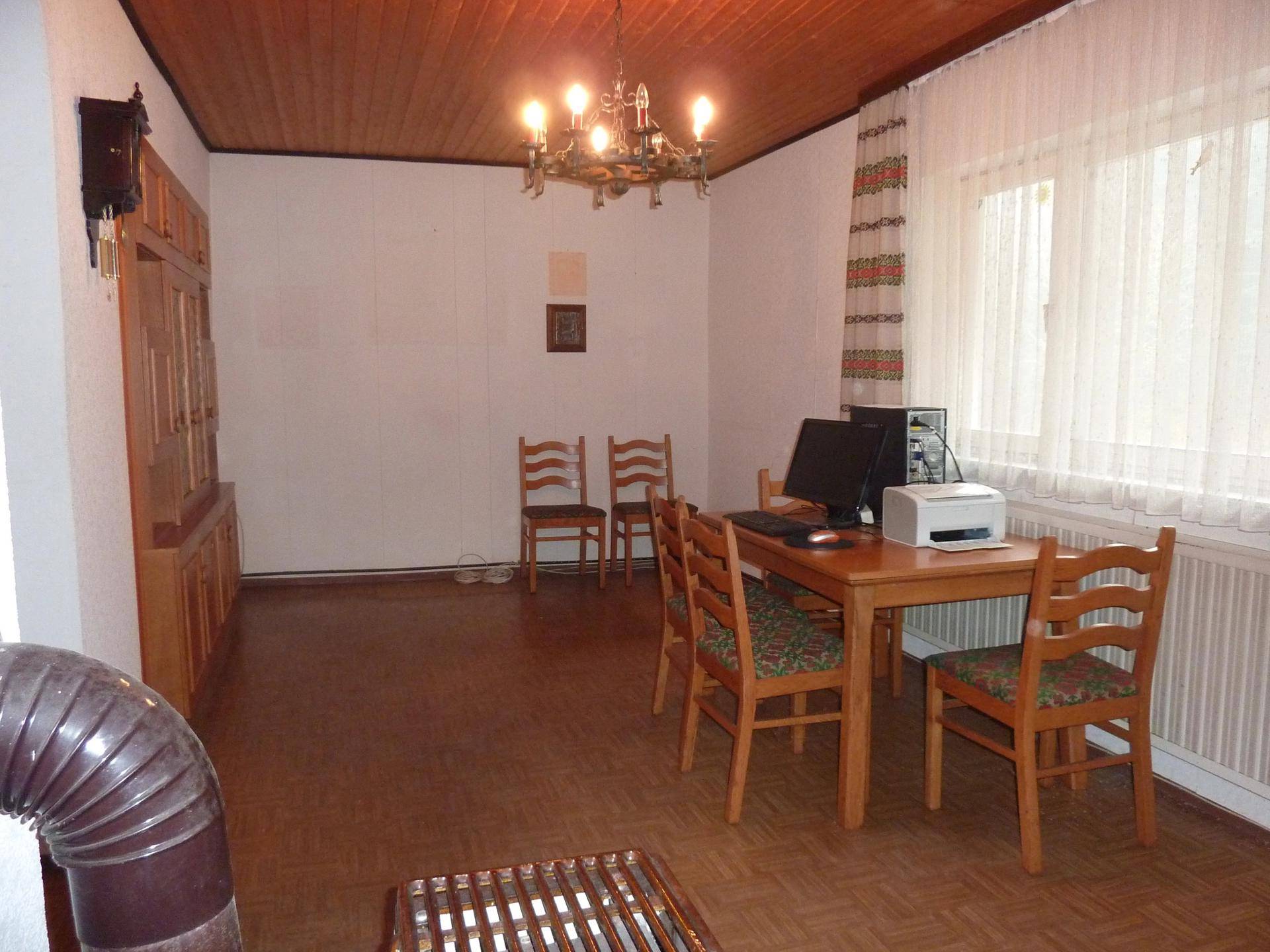 Arbeitszimmer mit Holzmöbeln, Schreibtisch und einem Kachelofen.