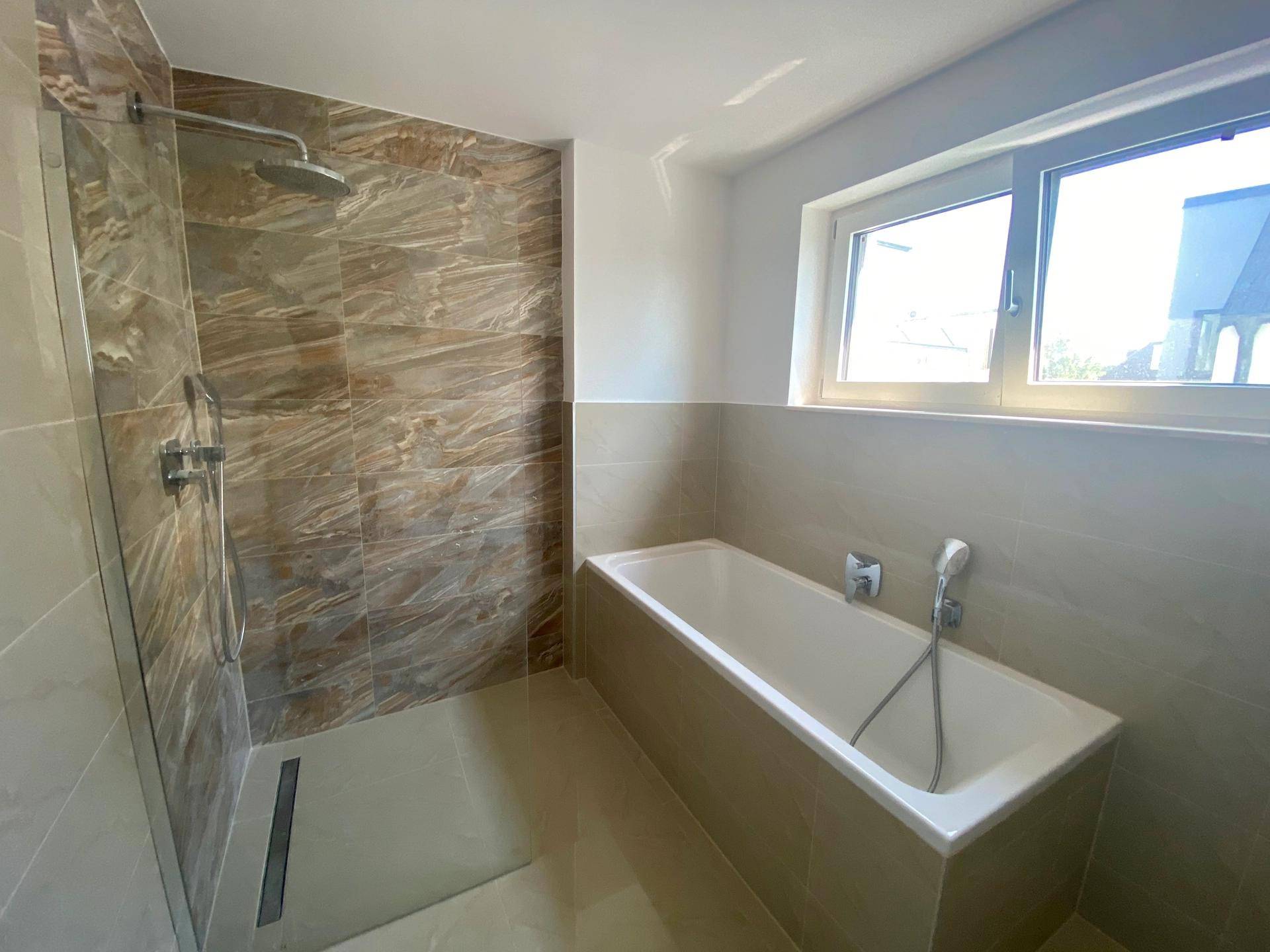 Modernes Badezimmer mit Badewanne, ebenerdiger Dusche und Fenster.