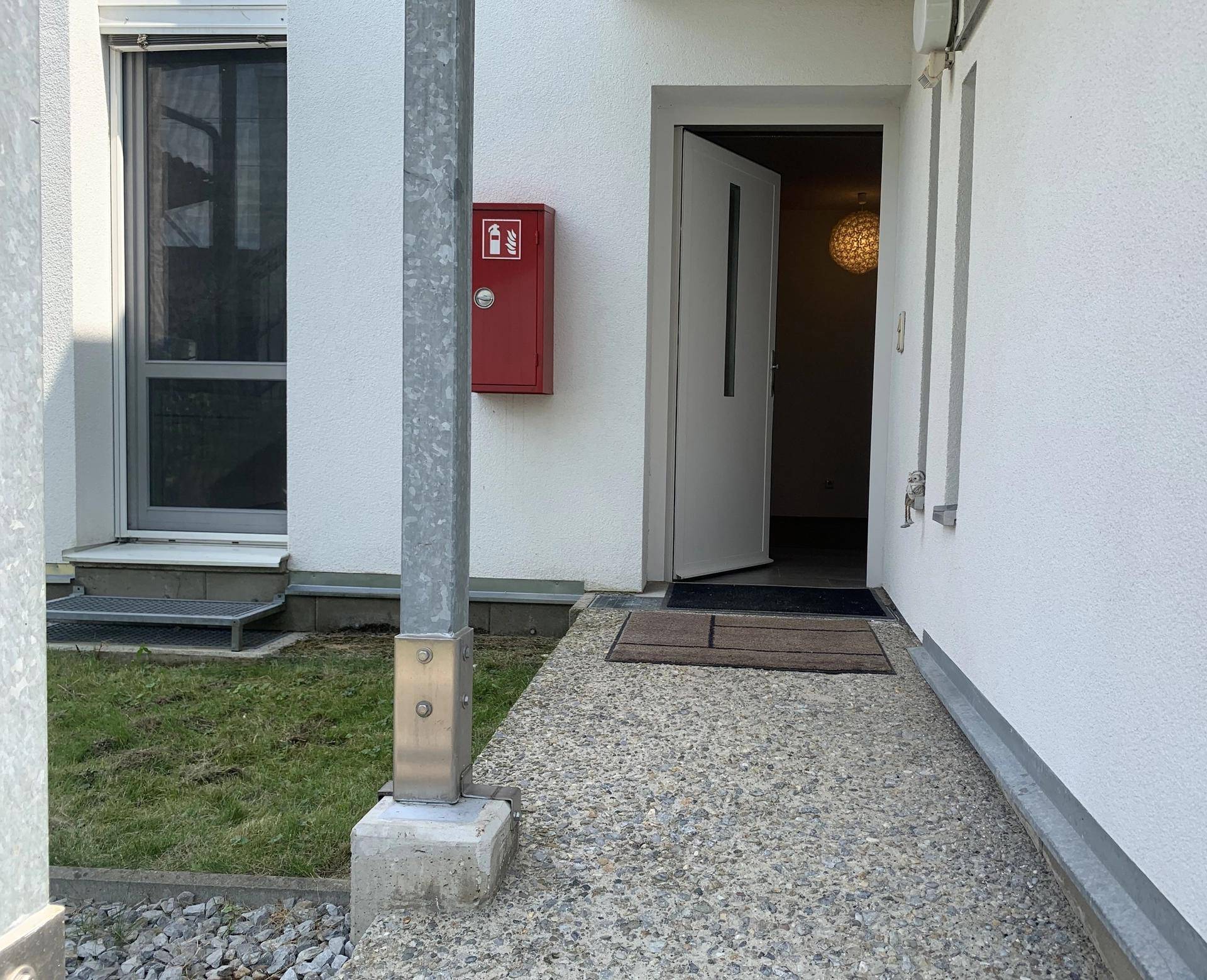 Barrierefreier Eingangsbereich mit einer Rampe und offener Haustür, die den Zugang erleichtert.