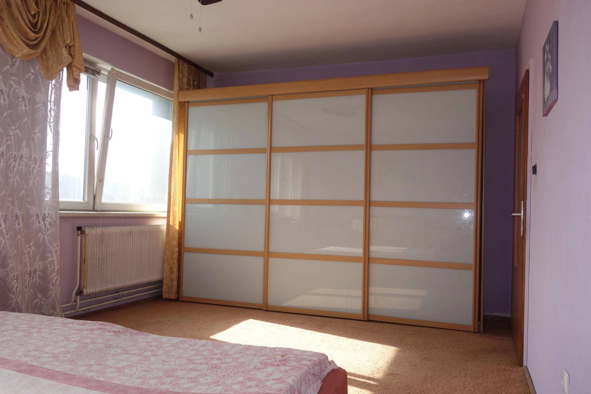 Schlafzimmer mit lila Wänden, Teppichboden und einem großen Schiebetürenschrank.