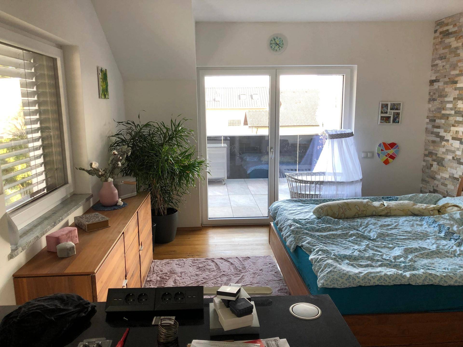 Gemütliches Schlafzimmer mit Holzboden, Zugang zum Balkon und viel Tageslicht.