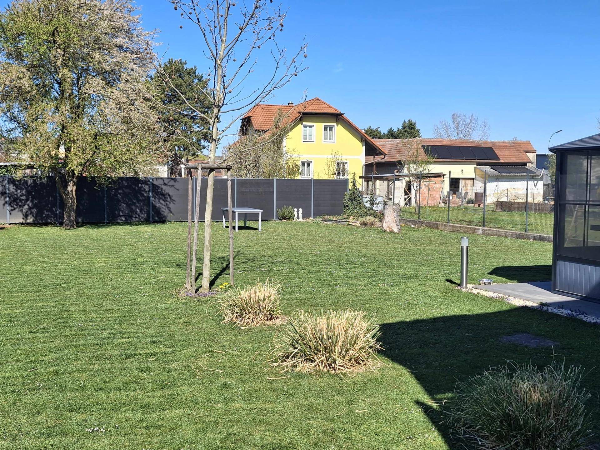 Weitläufiger Gartenbereich mit Rasenfläche und Blick auf die umliegende Nachbarschaft.