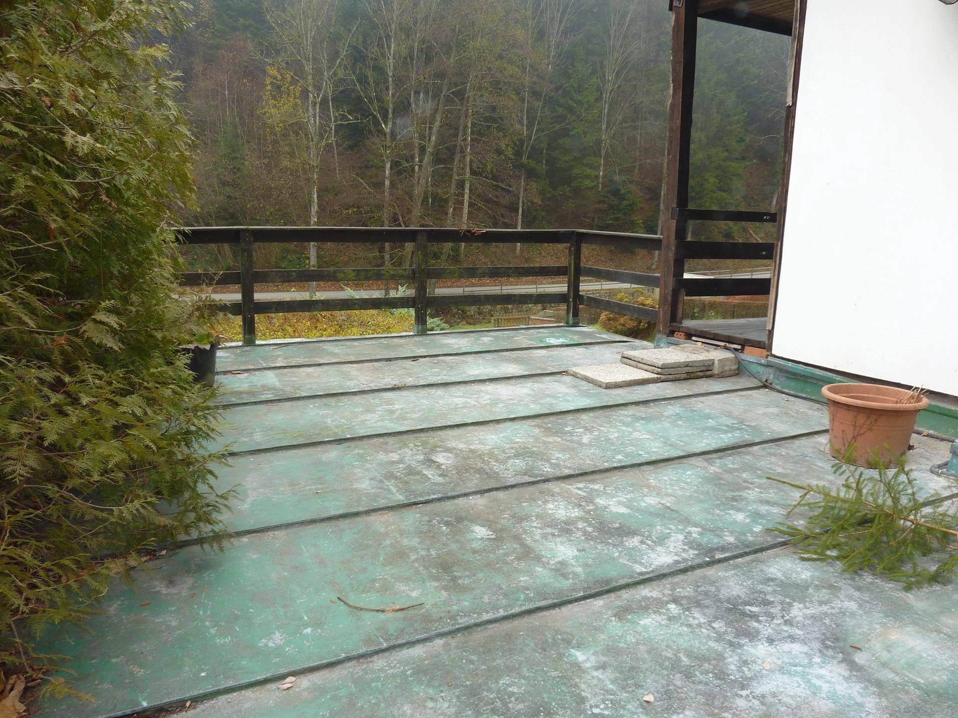 Terrasse mit Holzgeländer und Blick auf die bewaldete Hügellandschaft.