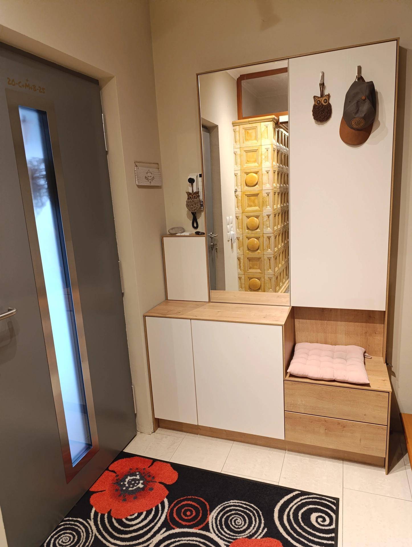 Eingangsbereich mit Garderobe, Spiegel und einem traditionellen Kachelofen im Hintergrund.