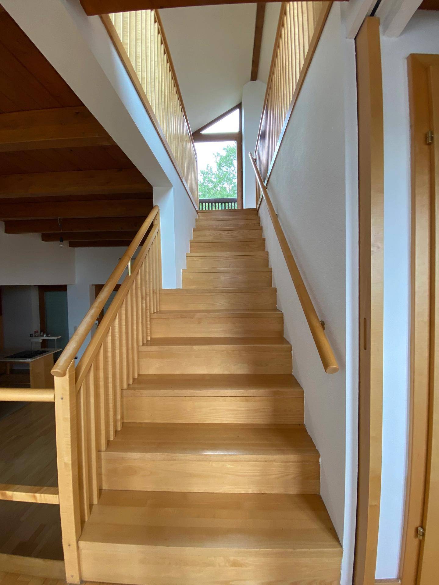 Helle Holztreppe mit Geländer, die verschiedene Ebenen des Hauses verbindet.