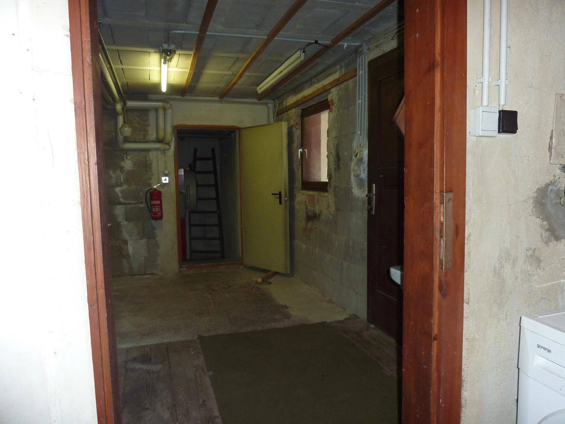 Kellerraum mit unverputzten Wänden, Betonboden und sichtbaren Installationen.