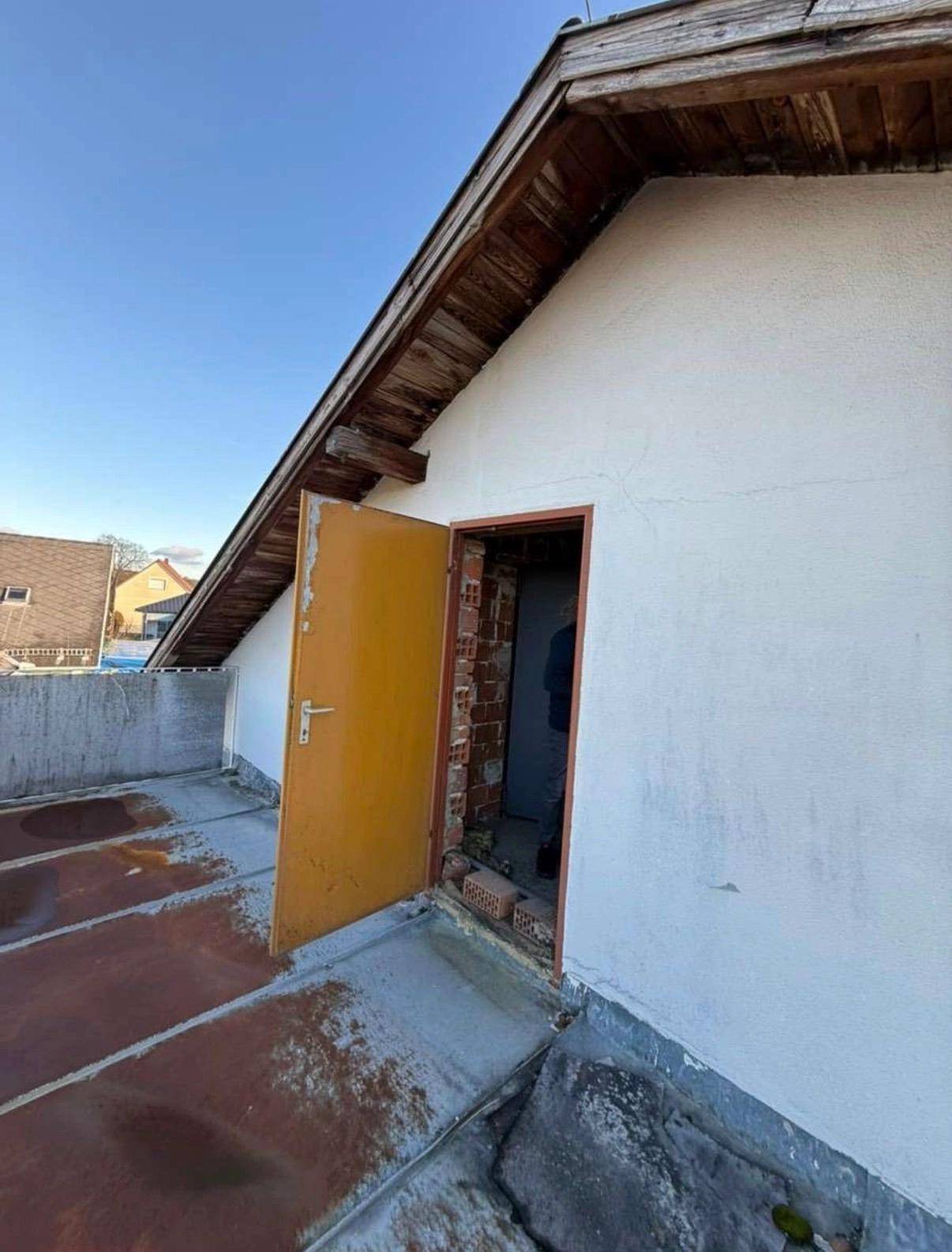 Dachbereich mit offener Tür und sichtbarer Holzkonstruktion, renovierungsbedürftig.
