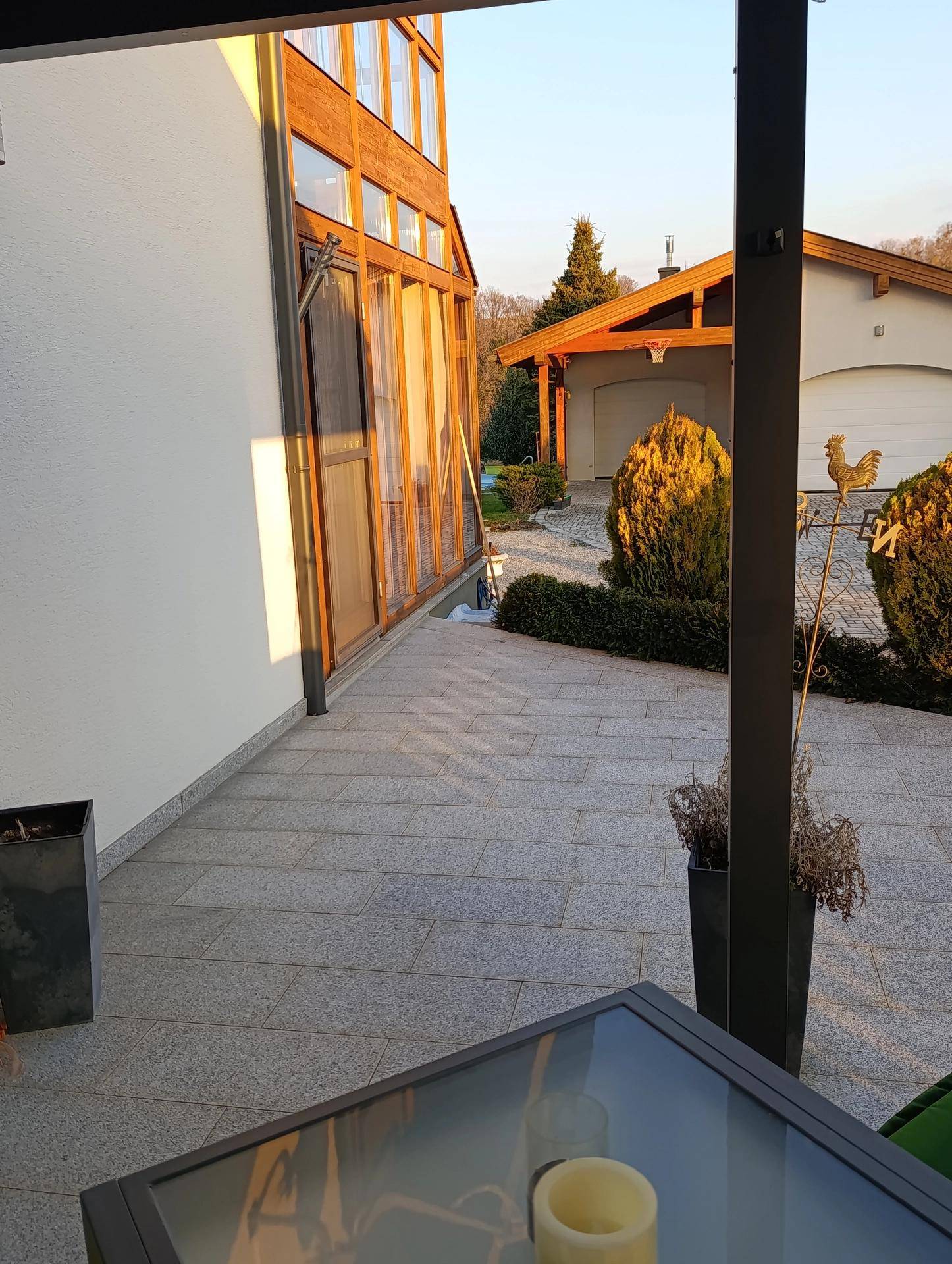Gepflasterte Terrasse mit Sitzgelegenheiten und Blick auf die Glasfassade des Hauses.