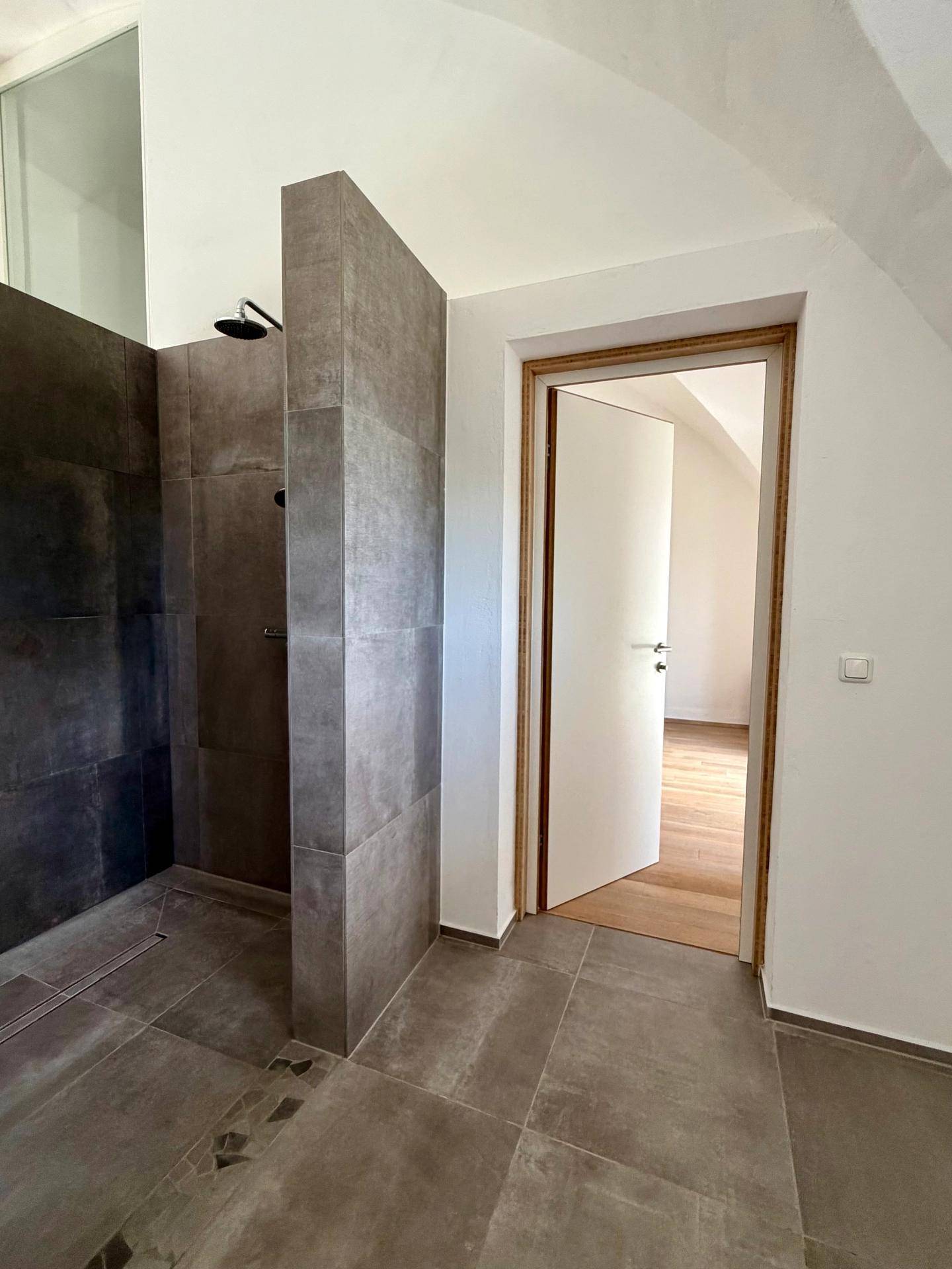 Gemütliches Zimmer mit gewölbter Decke, Holzboden und einem bequemen Schaukelstuhl, sehr hell.