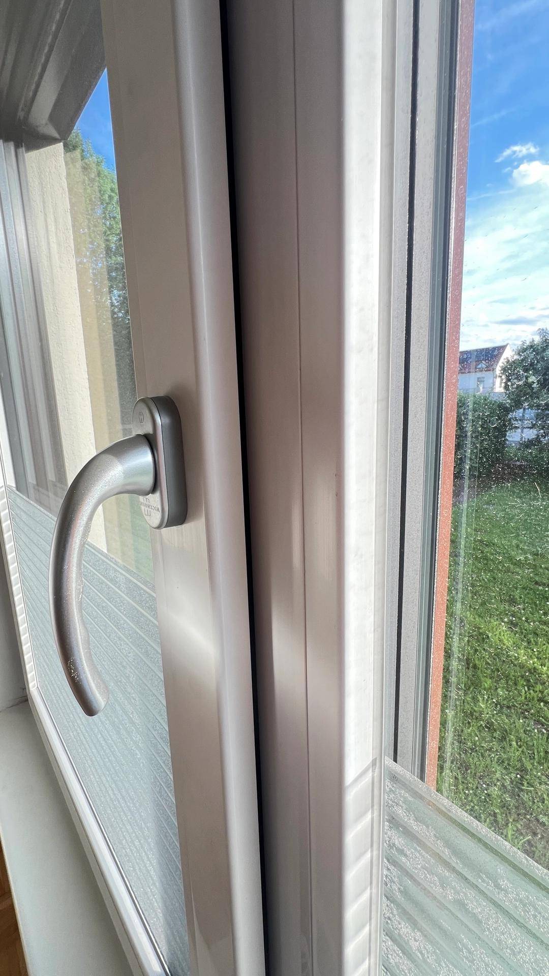 Nahaufnahme eines Fensters mit Blick auf die grüne Umgebung.