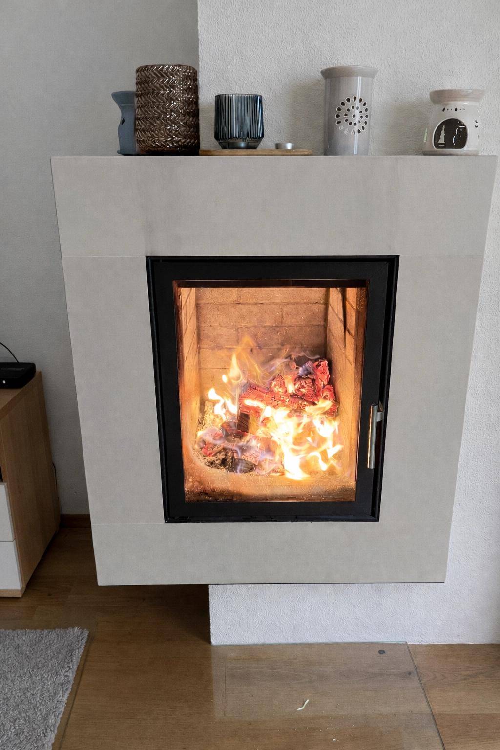 Moderner Kamin mit sichtbarem Feuer, umgeben von schlichten Dekorationen.