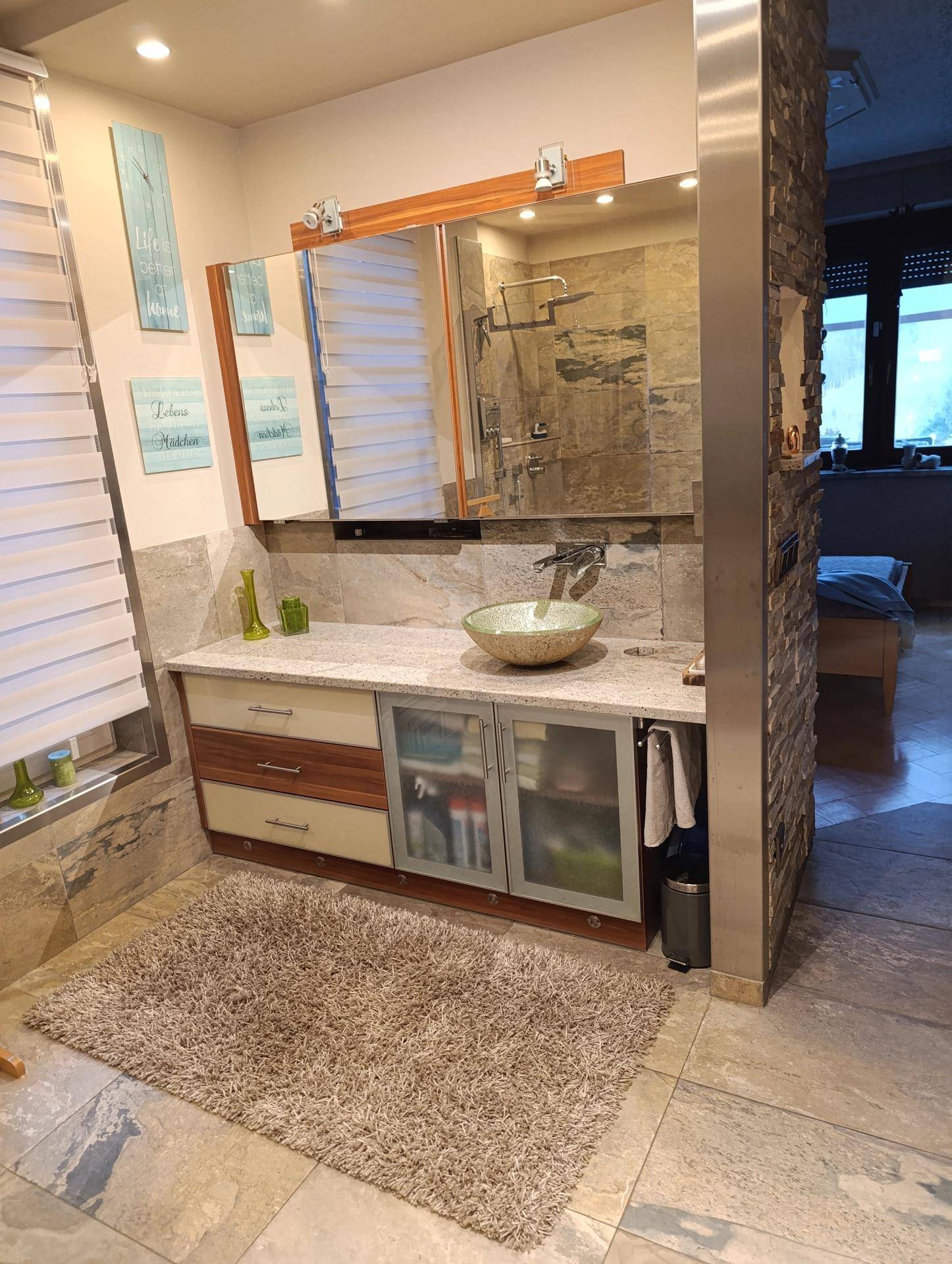 Modernes Badezimmer mit Doppelwaschbecken, begehbarer Dusche und Steinwand.