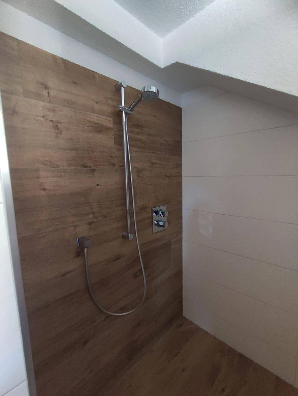 Moderne Duschkabine mit holzgemusterten Fliesen an Wand und Boden.