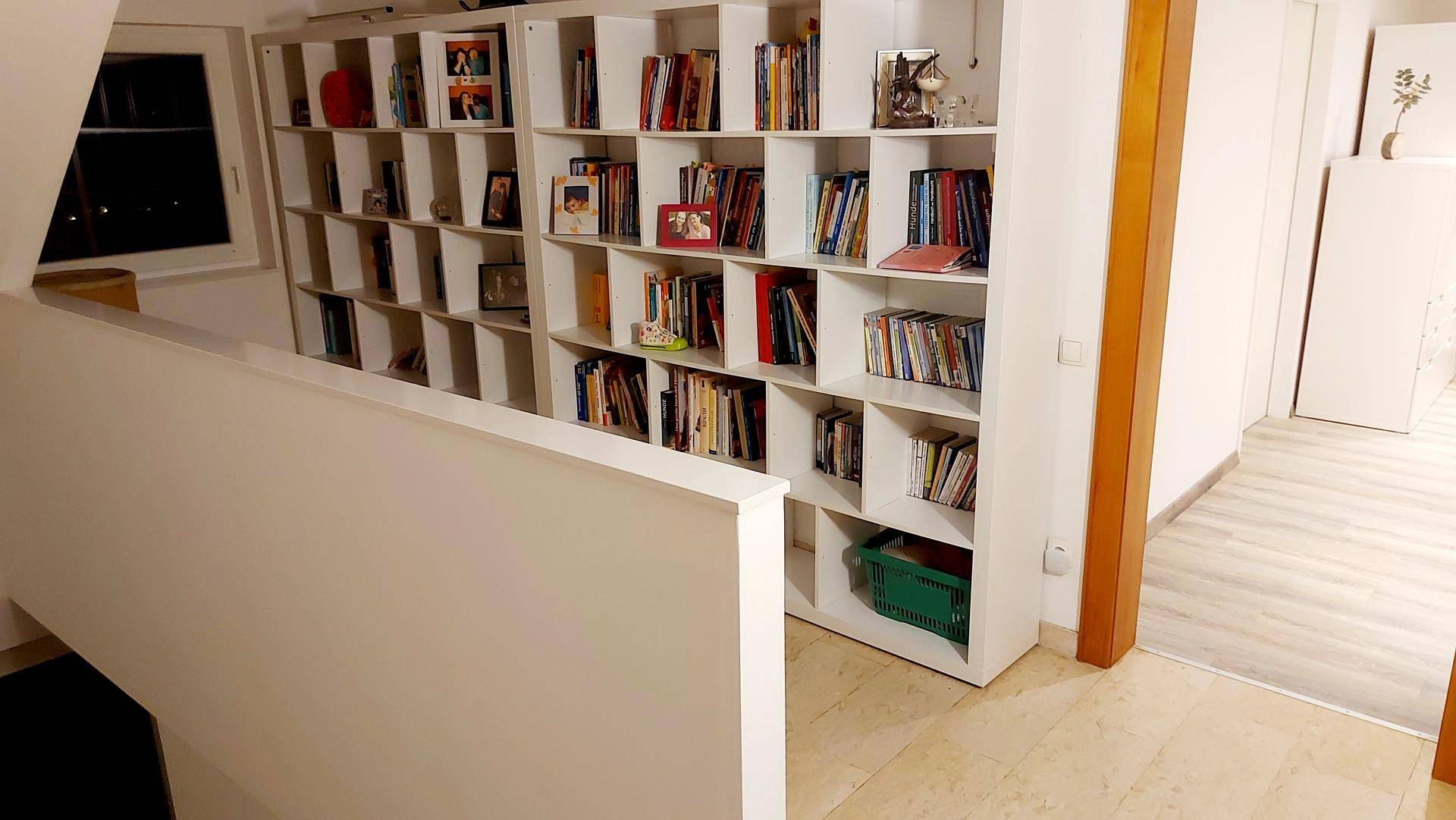 Heller Flur oder Treppenabsatz mit großem Bücherregal und Blick auf den Außenbereich.