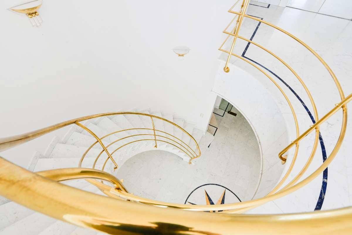 Elegante Wendeltreppe mit goldenem Geländer und Marmorstufen, die die verschiedenen Ebenen verbindet.