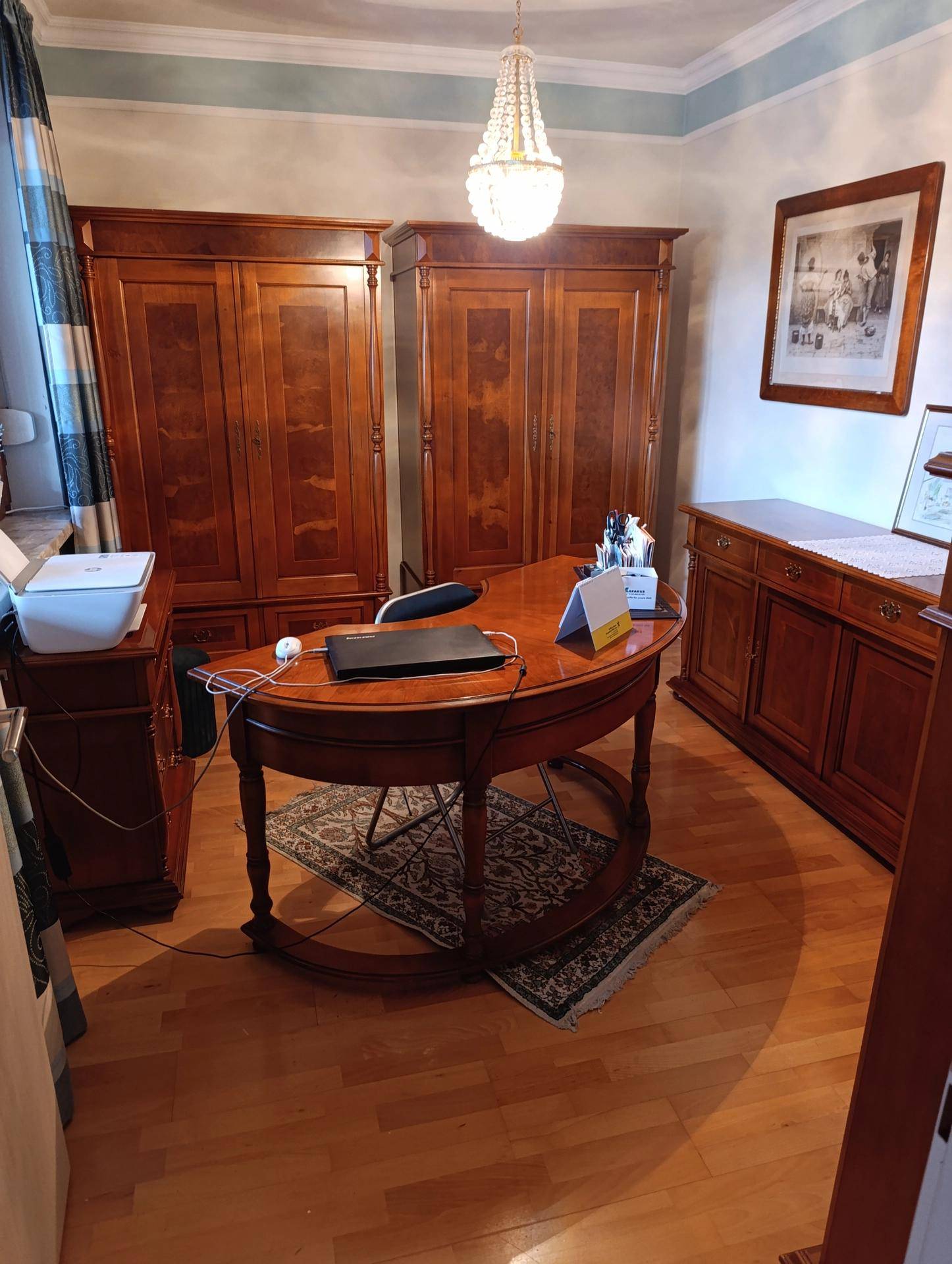 Klassisches Arbeitszimmer mit dunklen Holzmöbeln, Parkettboden und Kronleuchter.