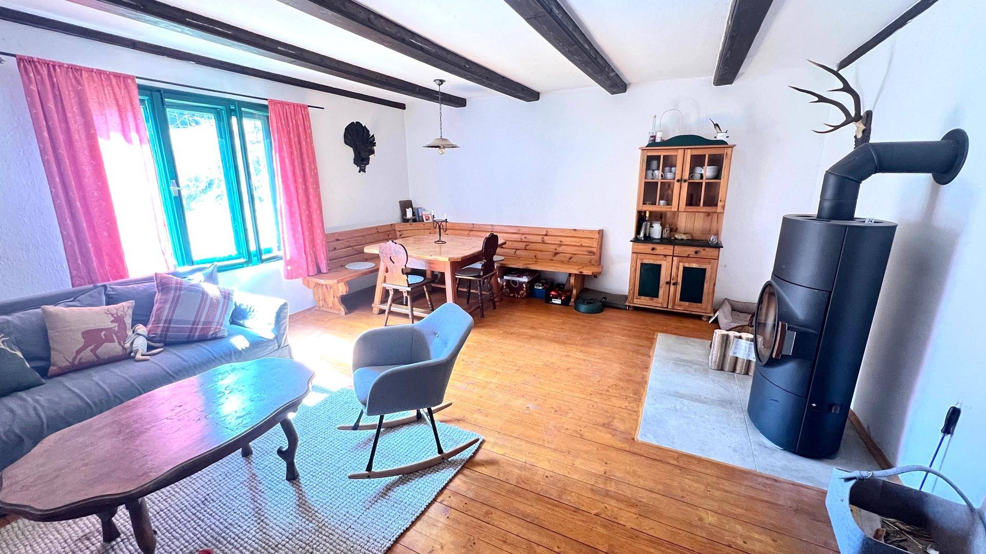 Geräumiger Wohn-Essbereich mit Holzboden, Kaminofen und rustikalen Holzmöbeln, hell und gemütlich.