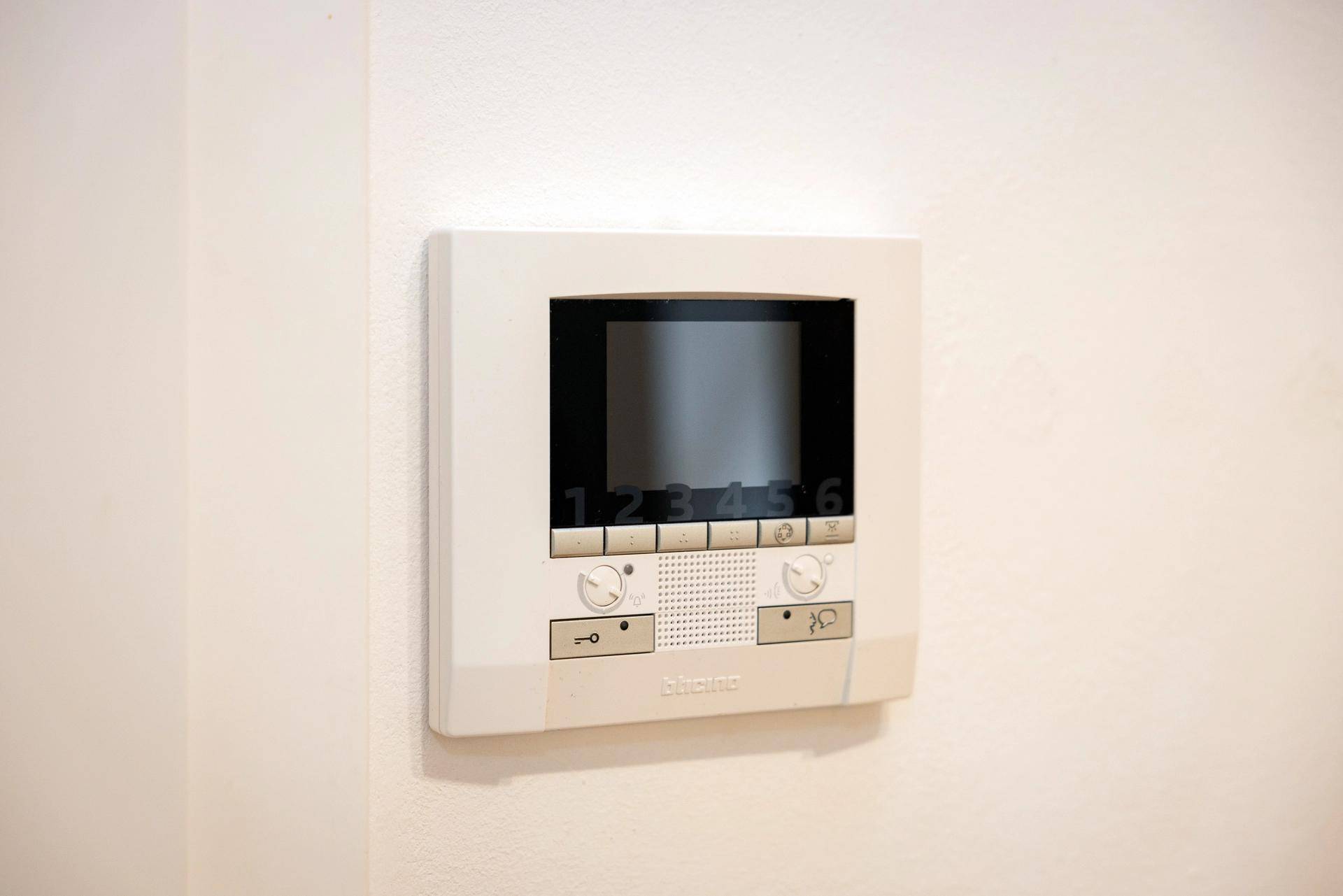 Eine moderne Gegensprechanlage mit Bildschirm an einer weißen Wand montiert.