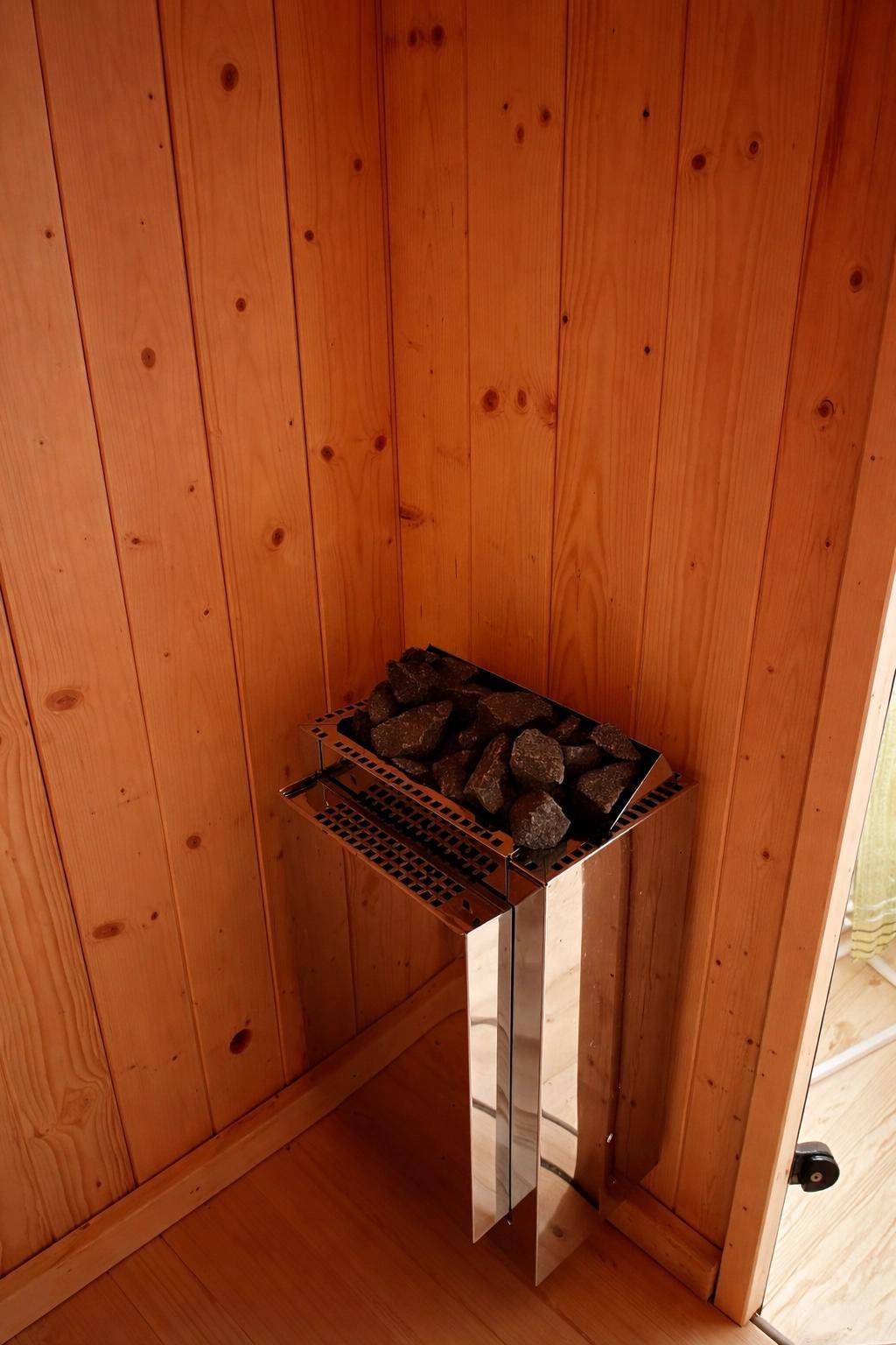 Saunaofen mit Steinen in einer holzvertäfelten Kabine, bereit zur Nutzung.