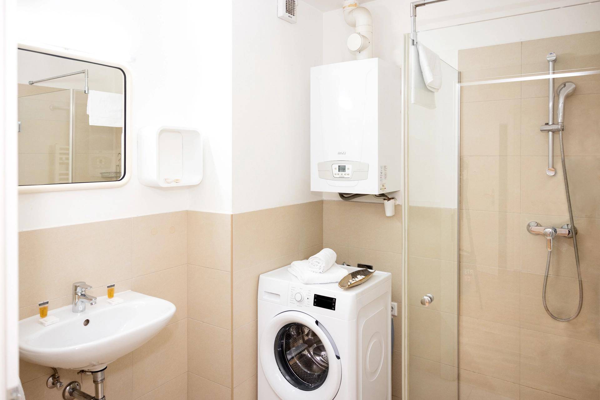 Modernes Badezimmer mit Dusche, Waschbecken und integrierter Waschmaschine.