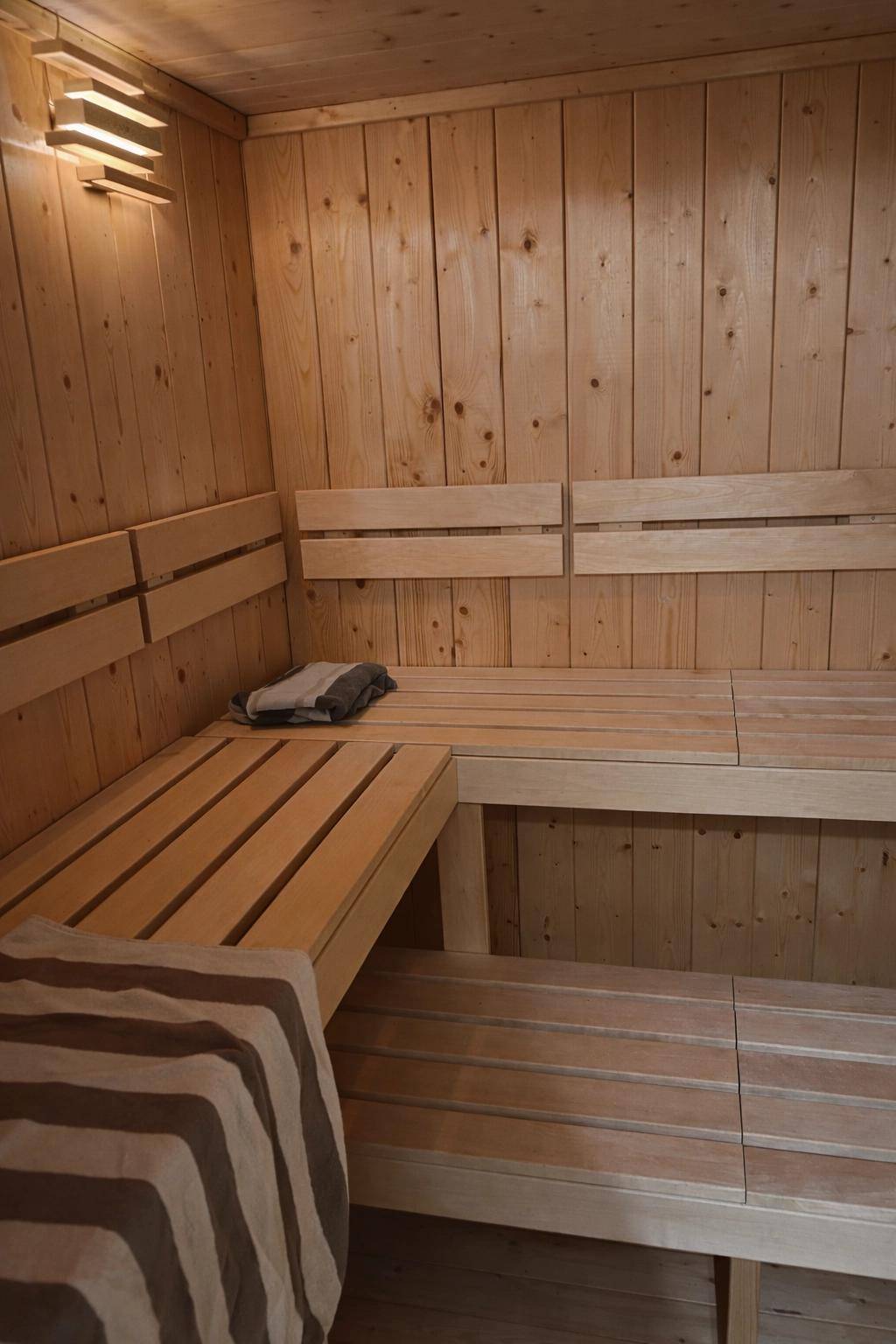 Holzvertäfelte Sauna mit mehrstufigen Bänken und gemütlicher Beleuchtung.