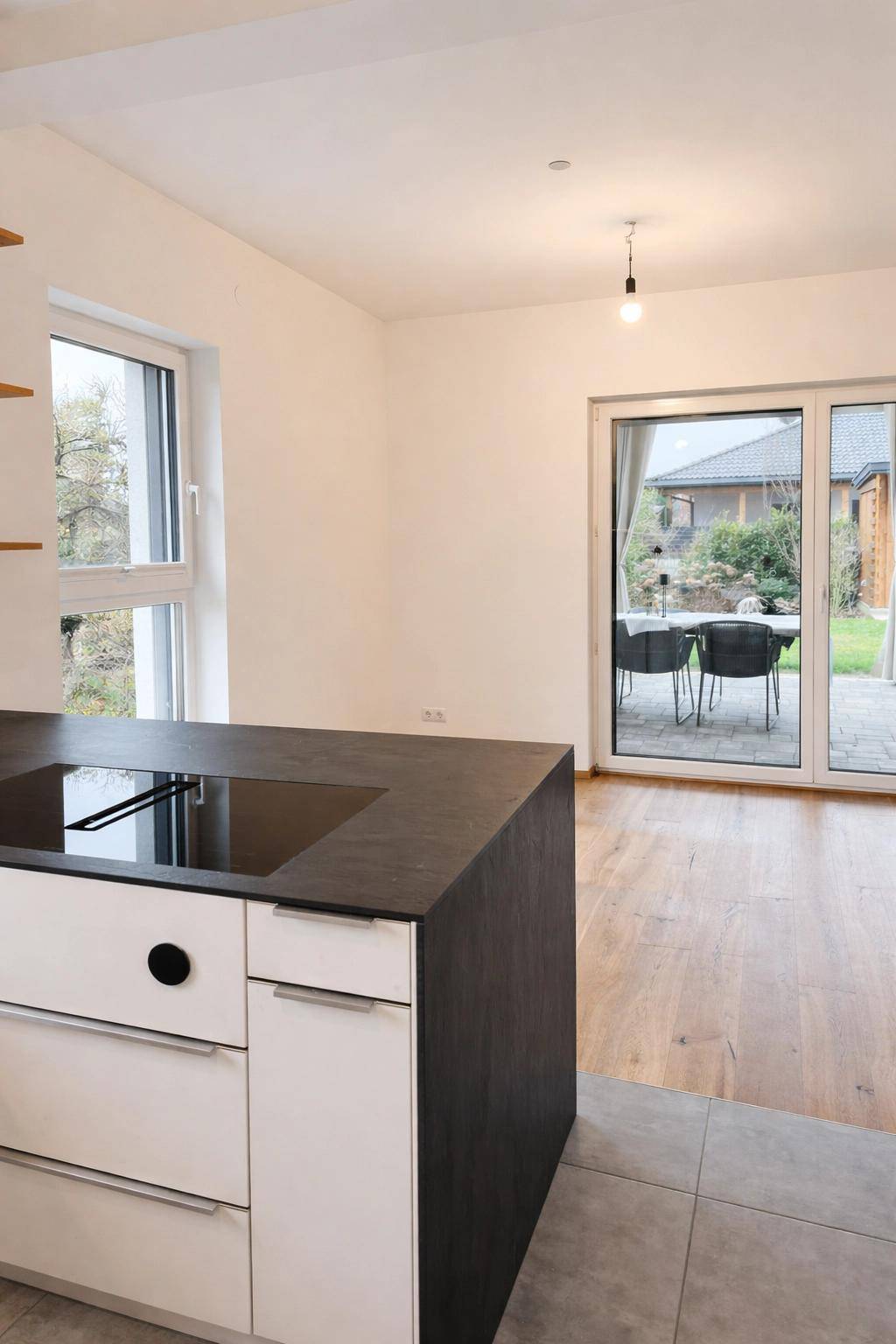 Offener Küchenbereich mit Kochinsel, Holzboden und Zugang zur Terrasse.