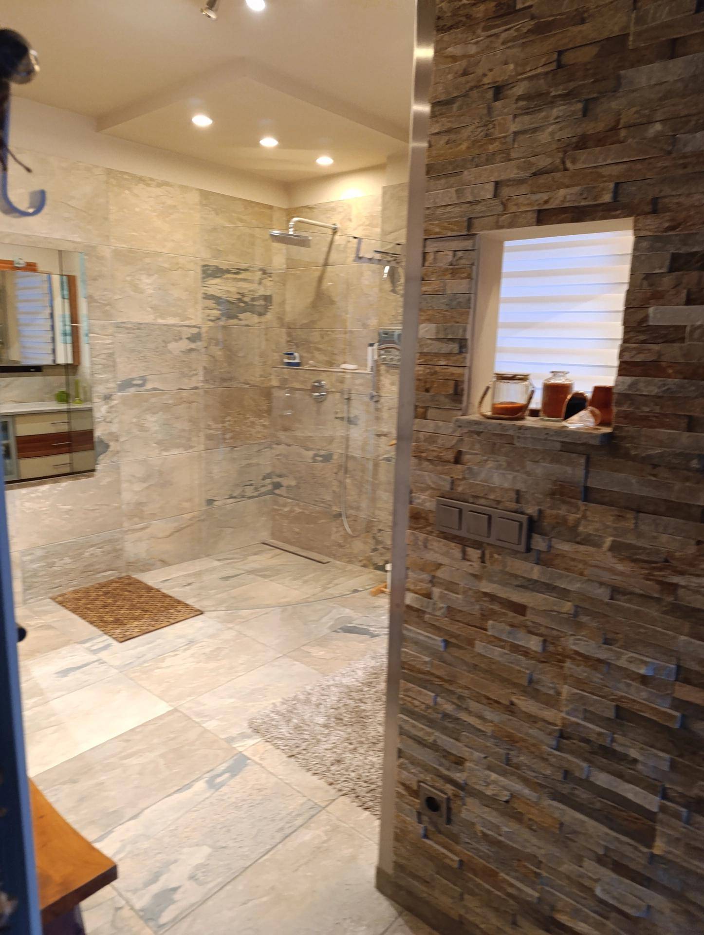 Geräumige begehbare Dusche mit Regenduschkopf und modernen Fliesen.