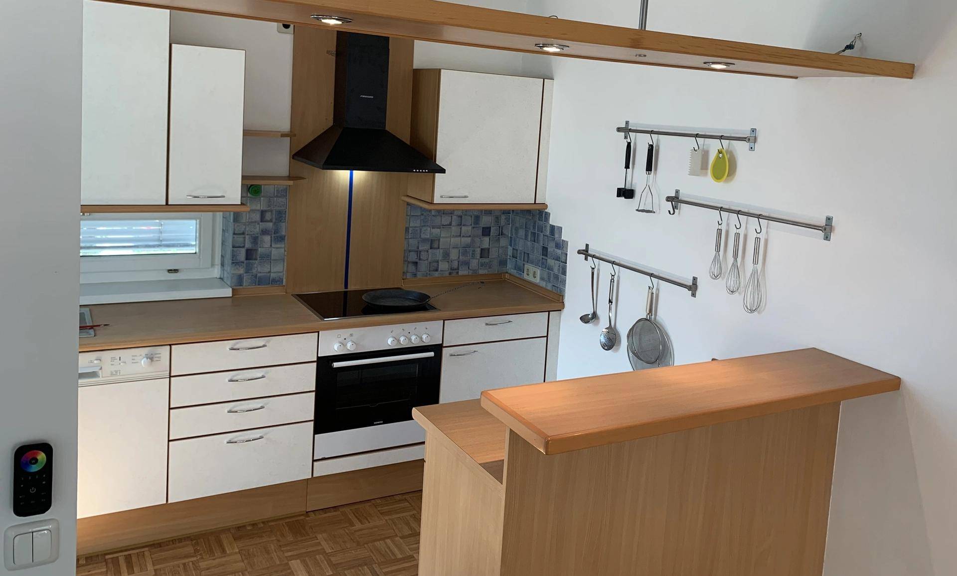 Funktionale Küche mit weißen Schränken, integrierten Geräten und einer praktischen Frühstücksbar.