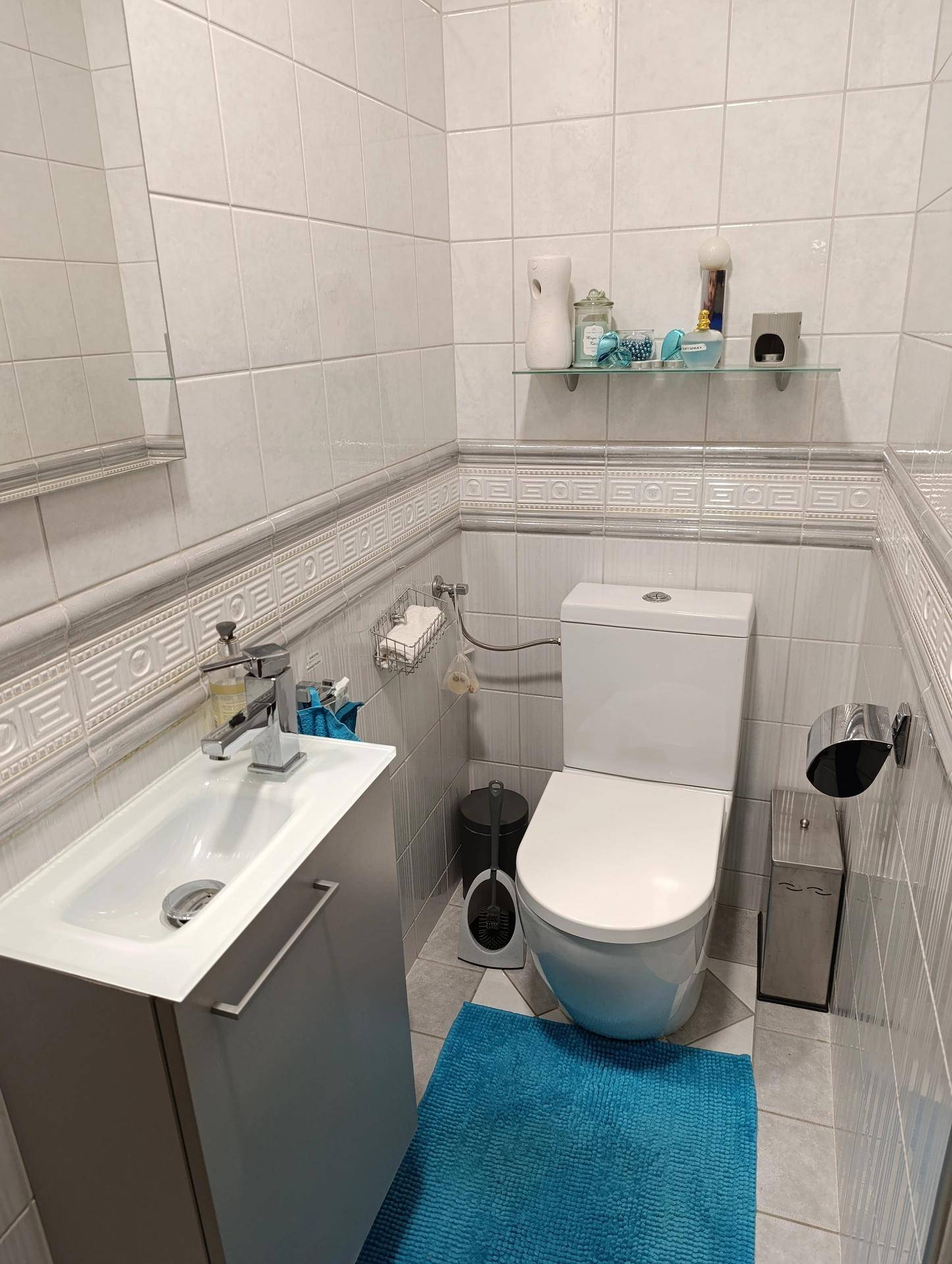 Kleines, hell gefliestes WC mit modernem Wand-WC und Waschtischunterschrank.