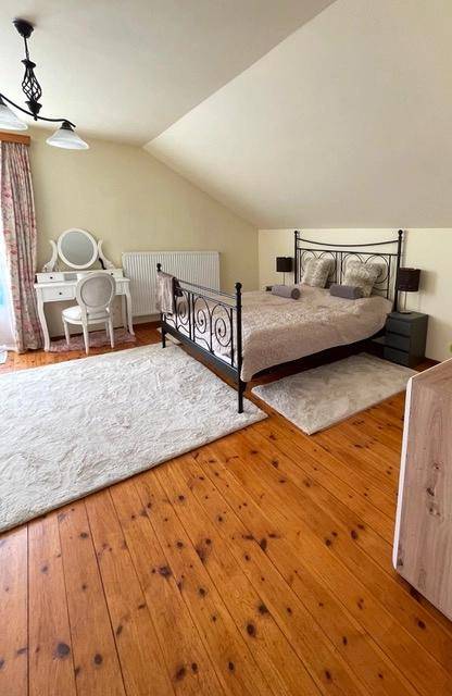 Gemütliches Schlafzimmer im Dachgeschoss mit Holzboden, Dachschrägen und Schminktisch.
