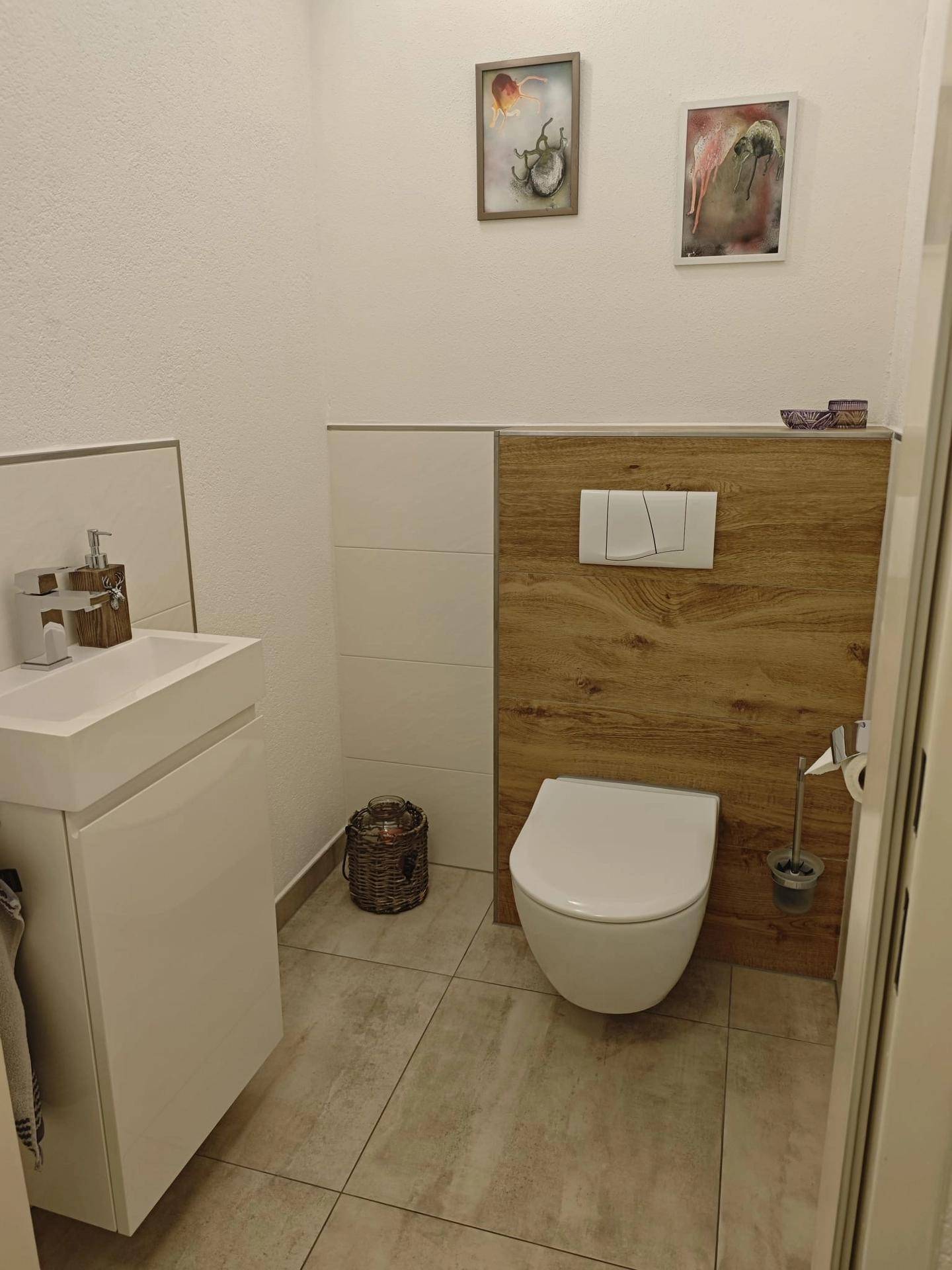 Helles Gäste-WC mit wandhängender Toilette und kleinem Waschbecken.