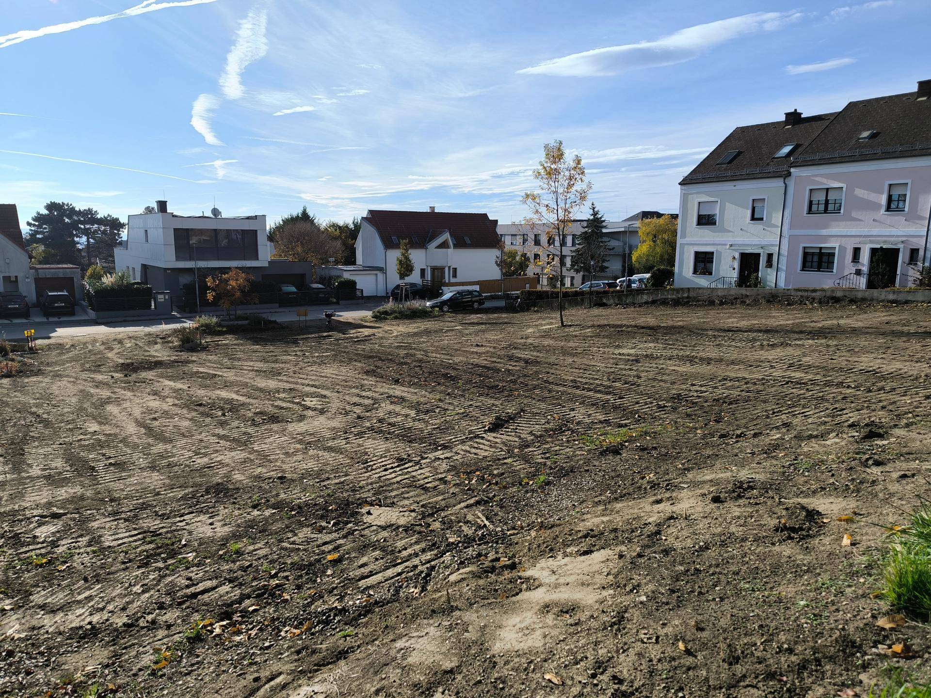 Geräumiges, frisch planiertes Grundstück mit umliegenden Wohnhäusern unter klarem Herbsthimmel.