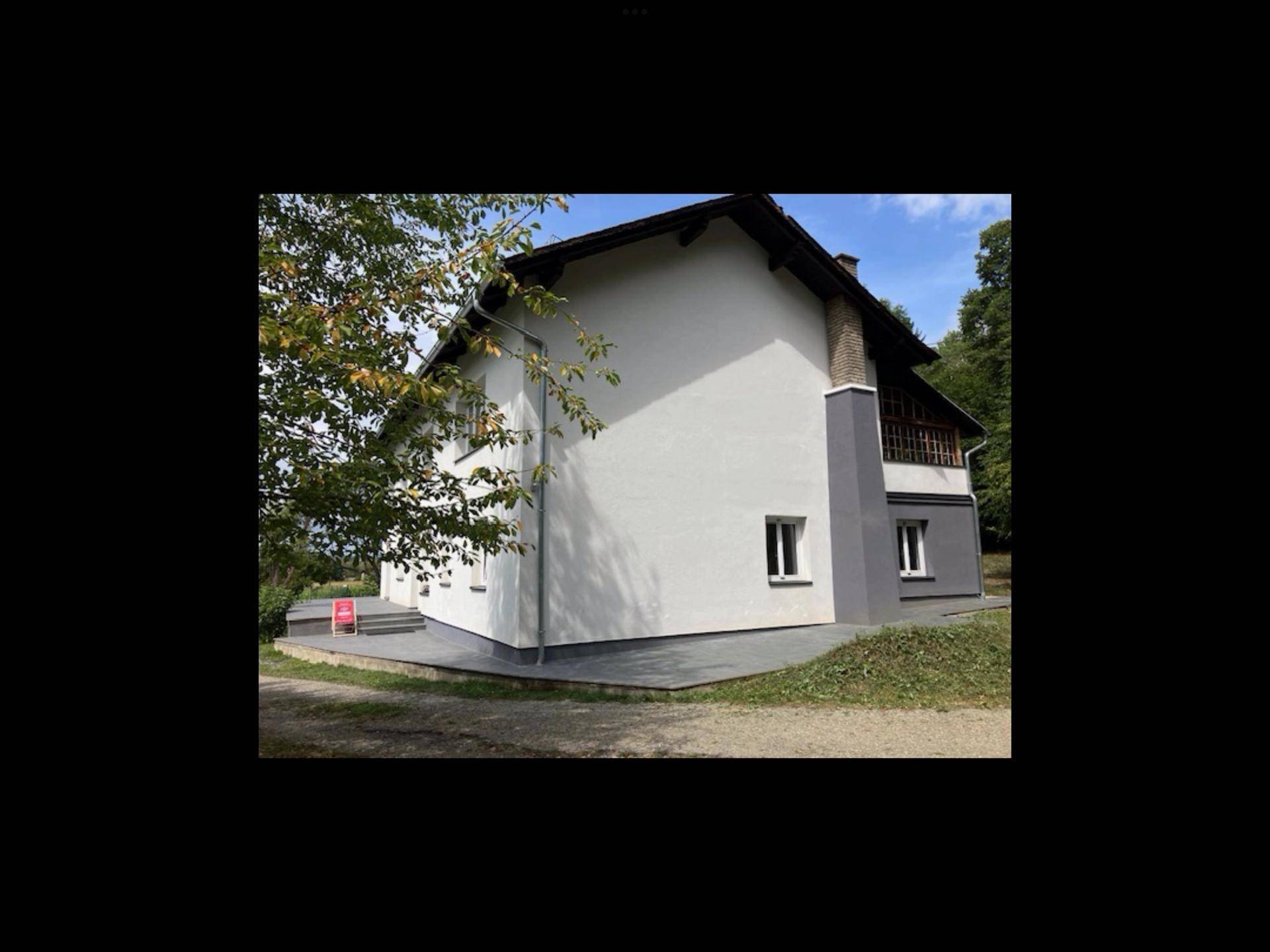 Moderne weiße Küche mit schwarzen Arbeitsplatten und Fliesenboden, offen zum Flur.