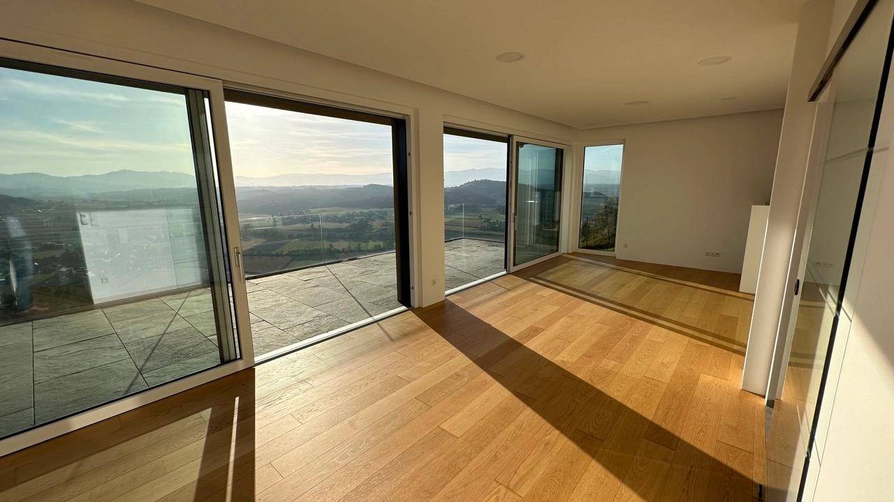 Lichtdurchfluteter Wohnbereich mit Holzboden und großen Schiebetüren, die einen weiten Landschaftsblick bieten.